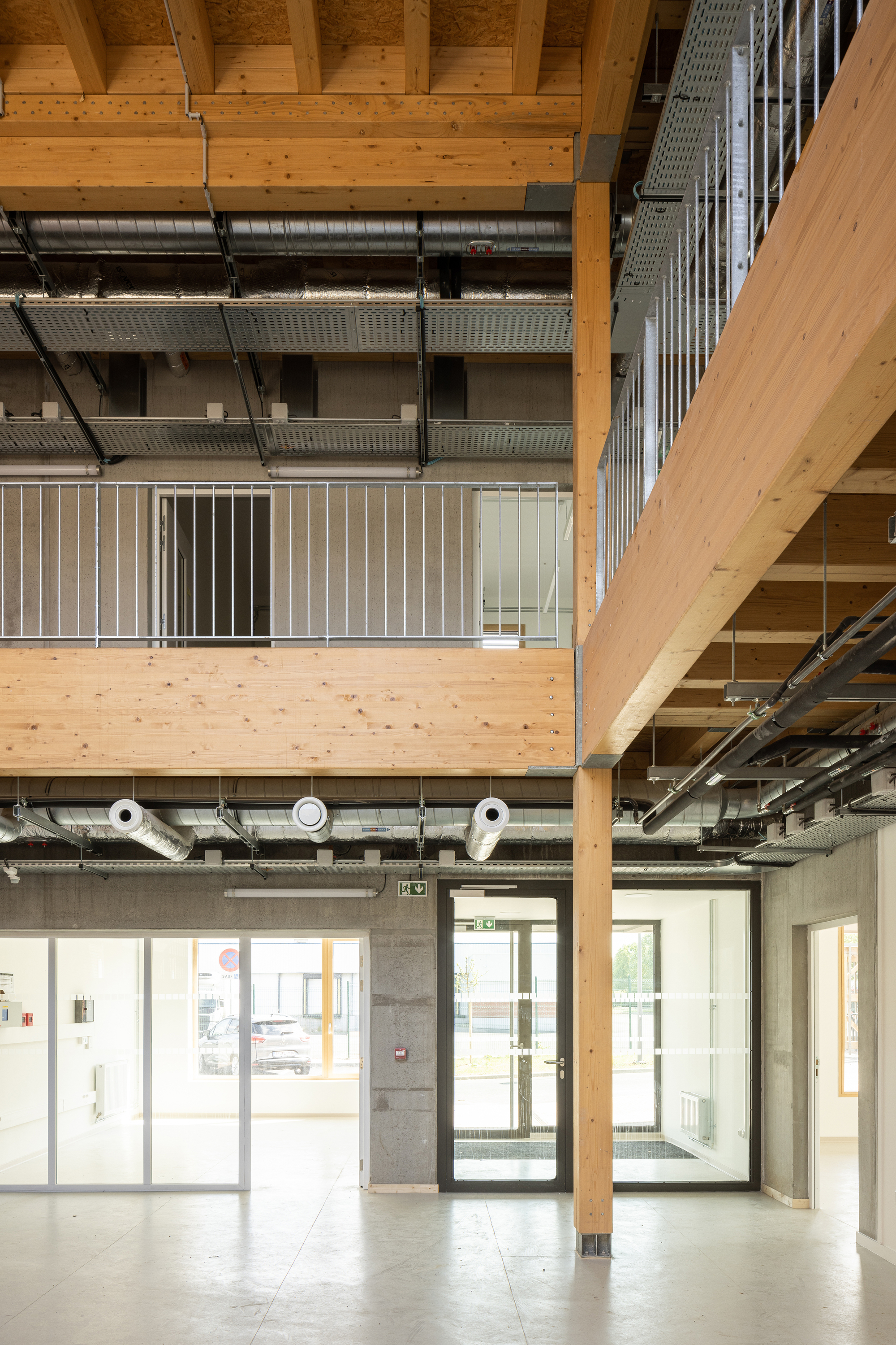 Double-height interior atrium with exposed timber beams and metal ductwork spanning across levels
