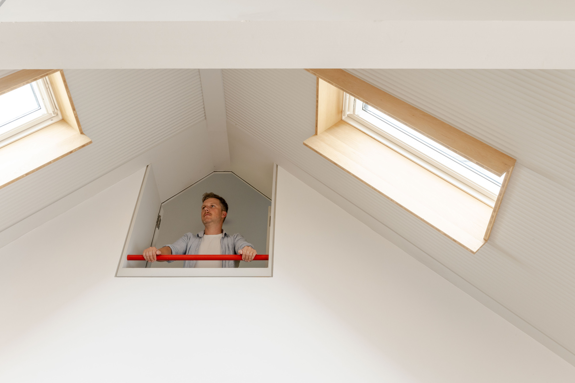 Person looking down through pentagonal hatch in vaulted ceiling with two skylights