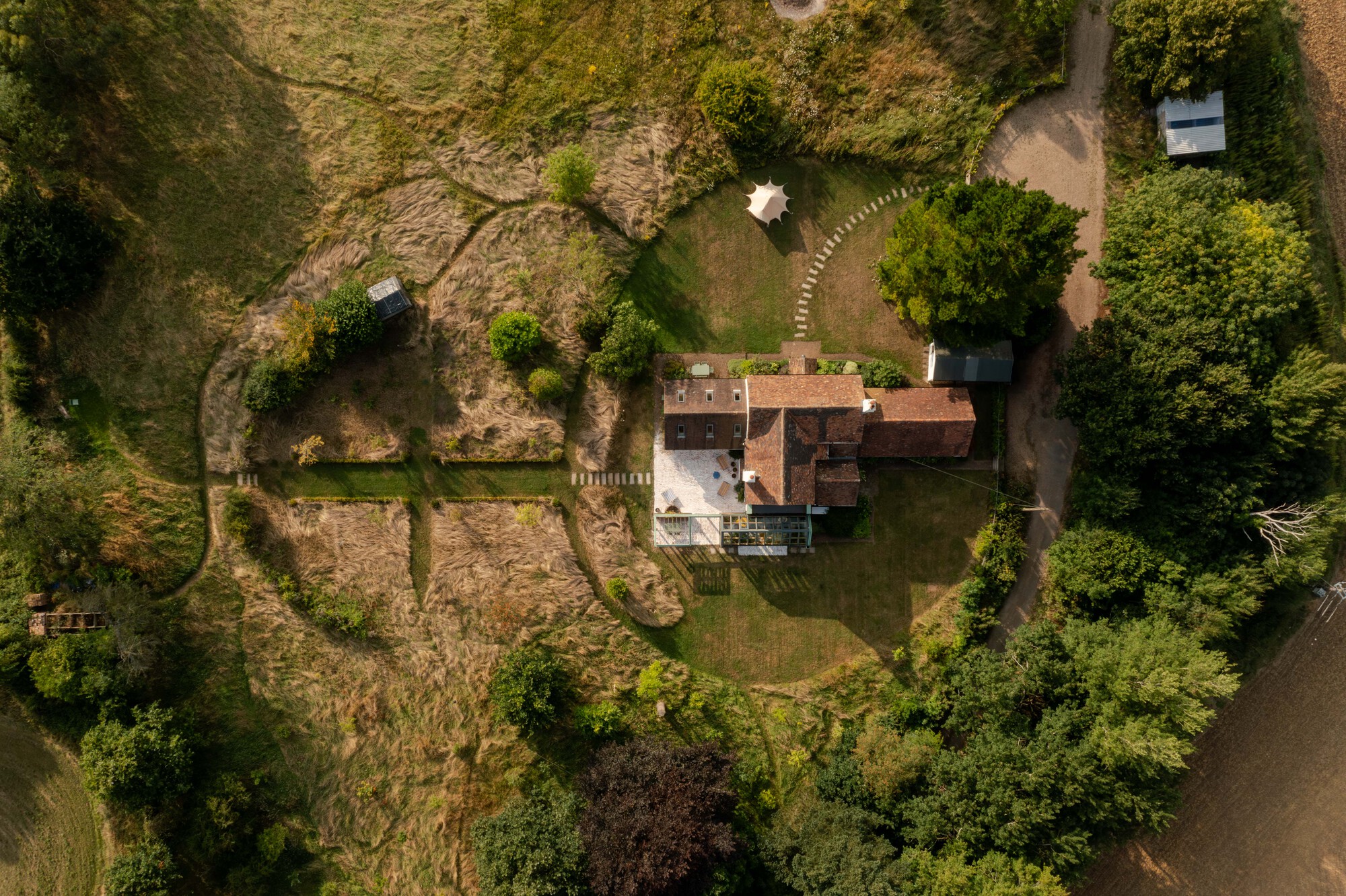 Aerial view of the house and its terracotta roof surrounded by gardens and deciduous trees