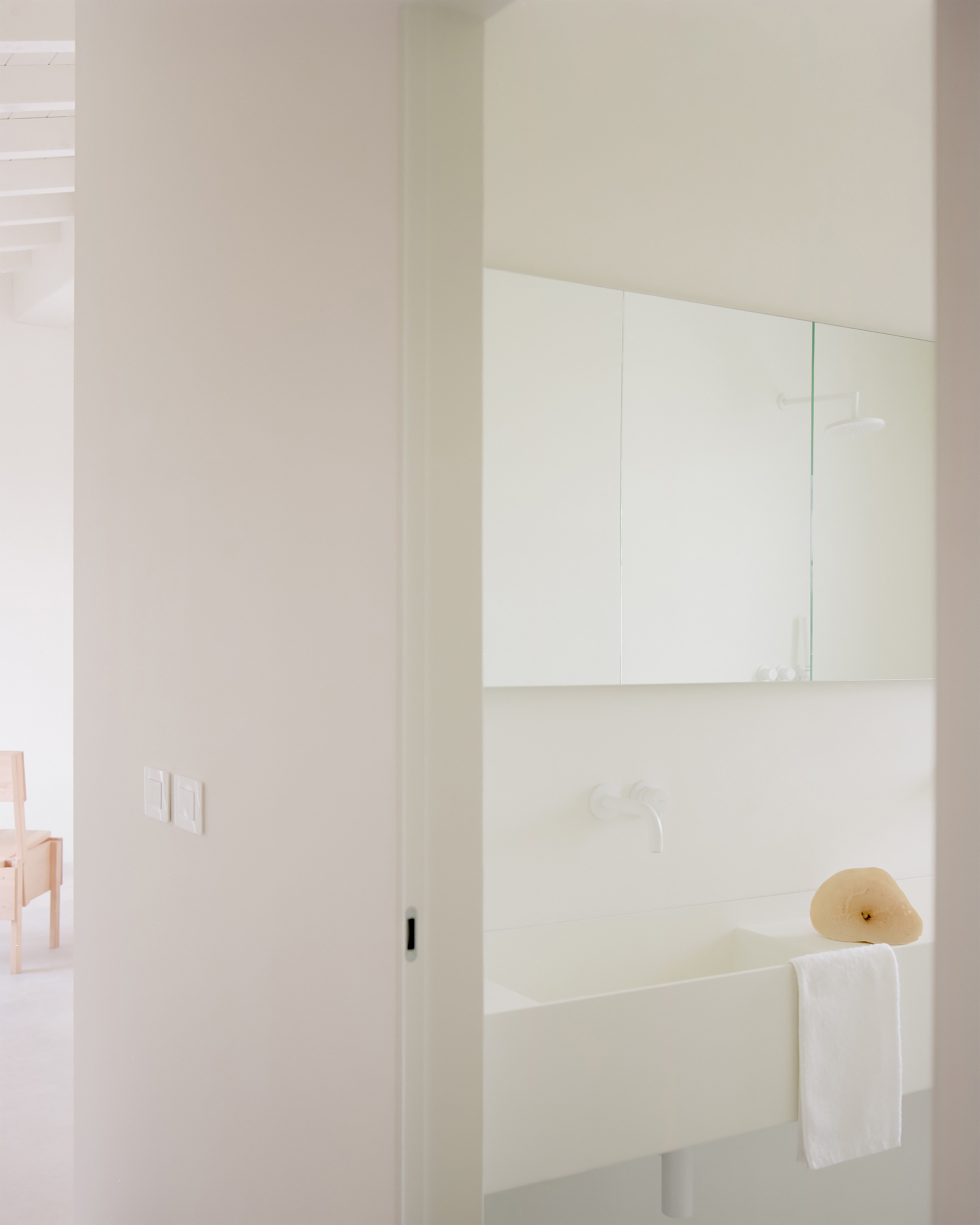 Wall-mounted vanity with recessed cabinet and wooden hat resting on the white countertop