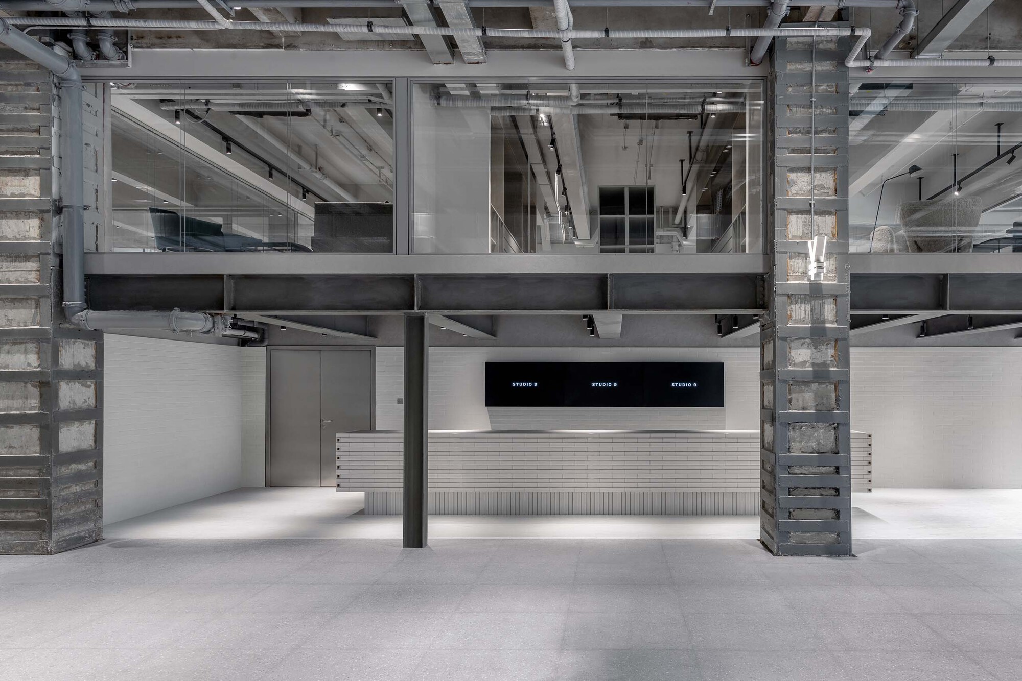 Interior view of double-height space with exposed concrete columns, steel beams, and central service counter