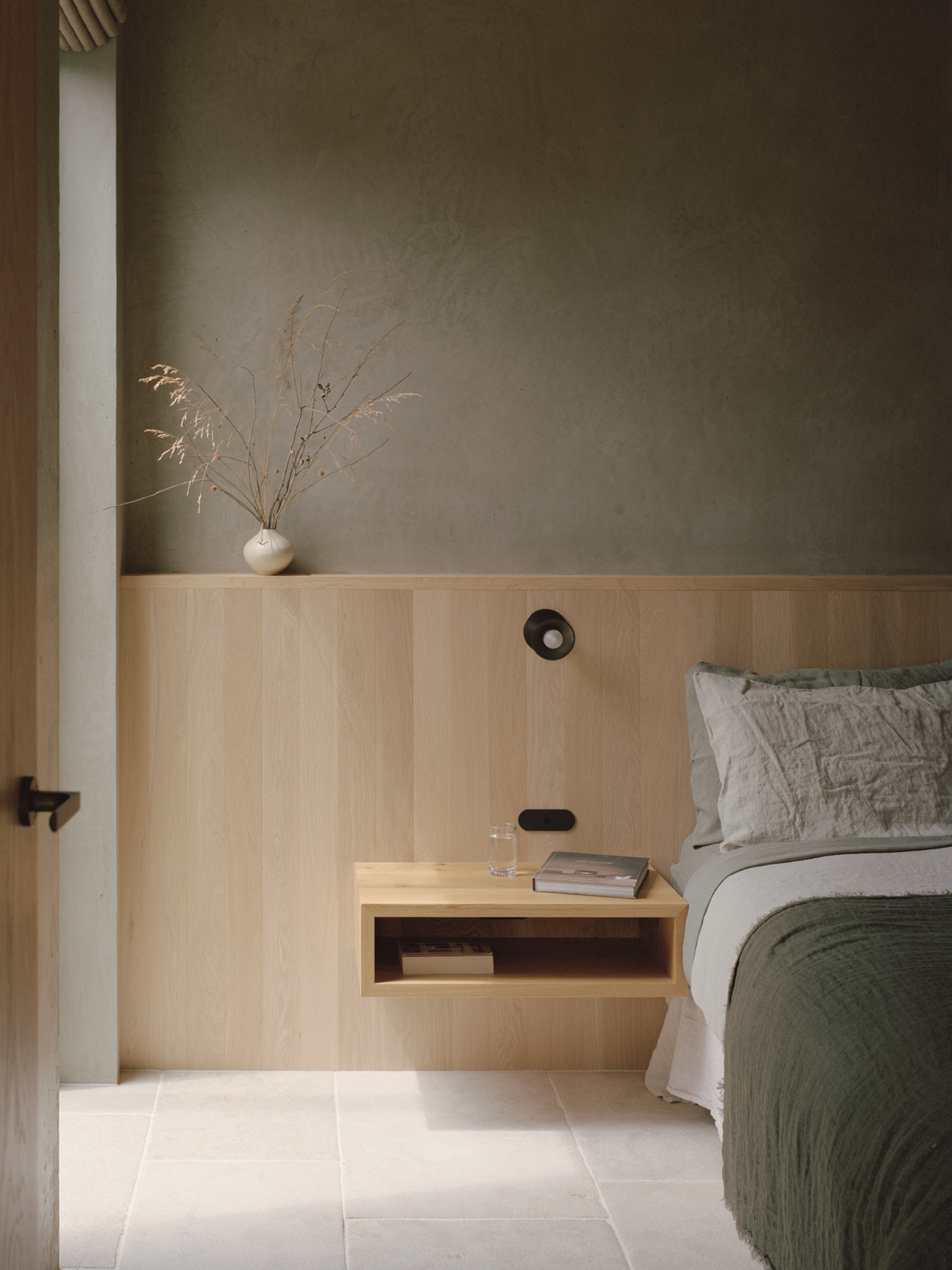 Bedroom wall detail with timber wainscoting and integrated floating nightstand in soft morning light