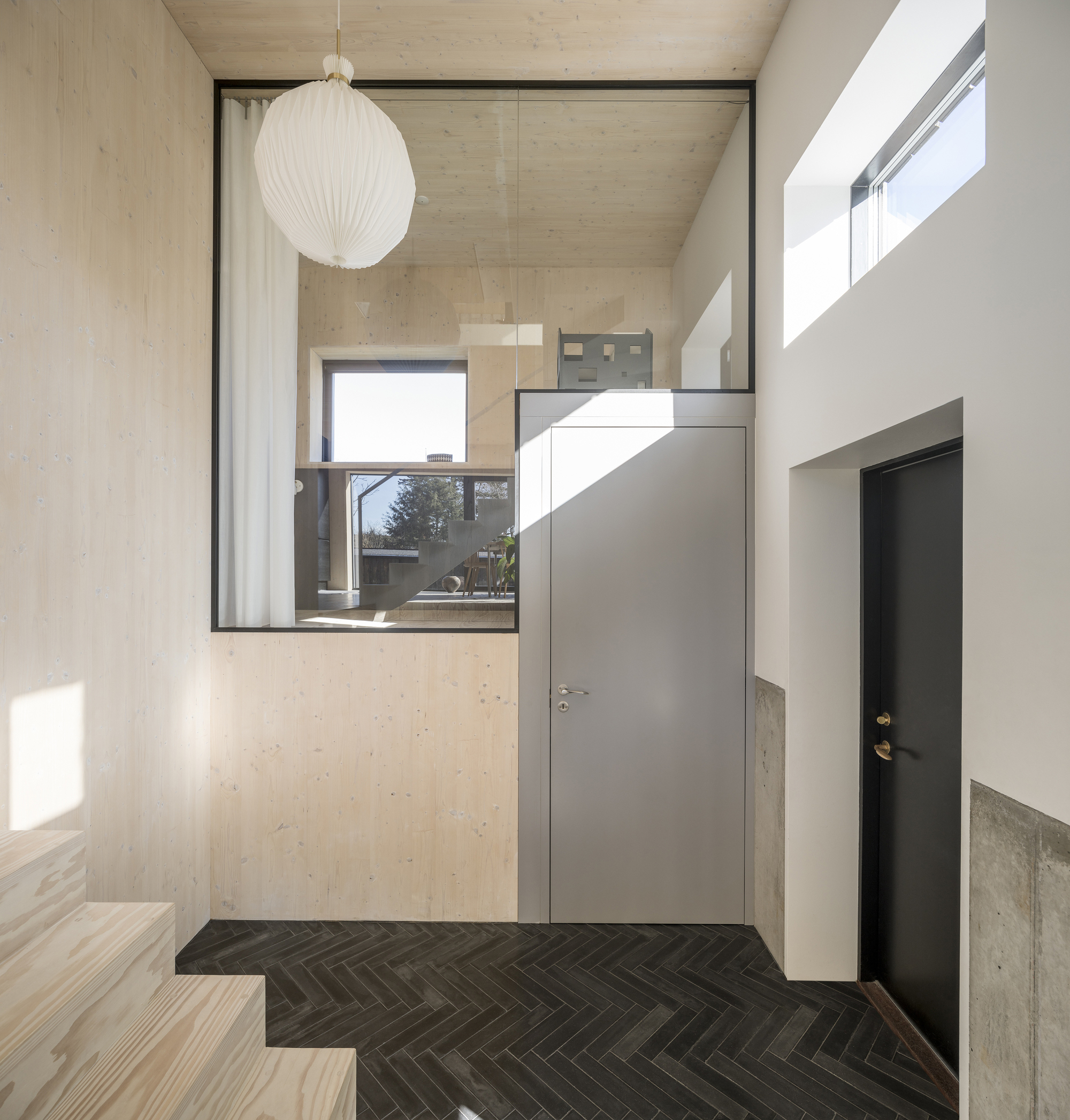 Entry hall with herringbone tile floor and grey doors beneath a spherical pendant lamp