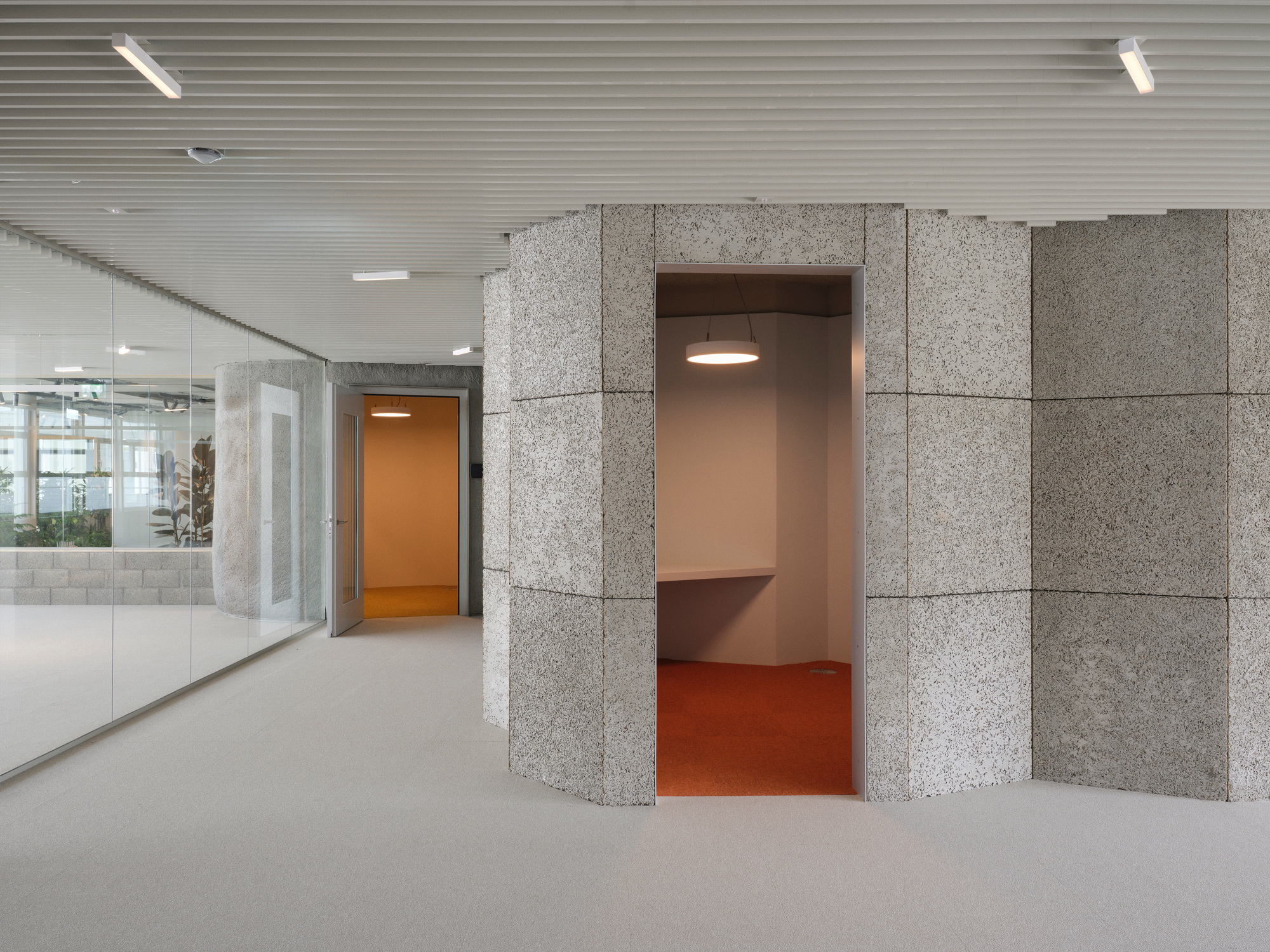 Exposed aggregate concrete alcove with orange interior recess and door visible in background