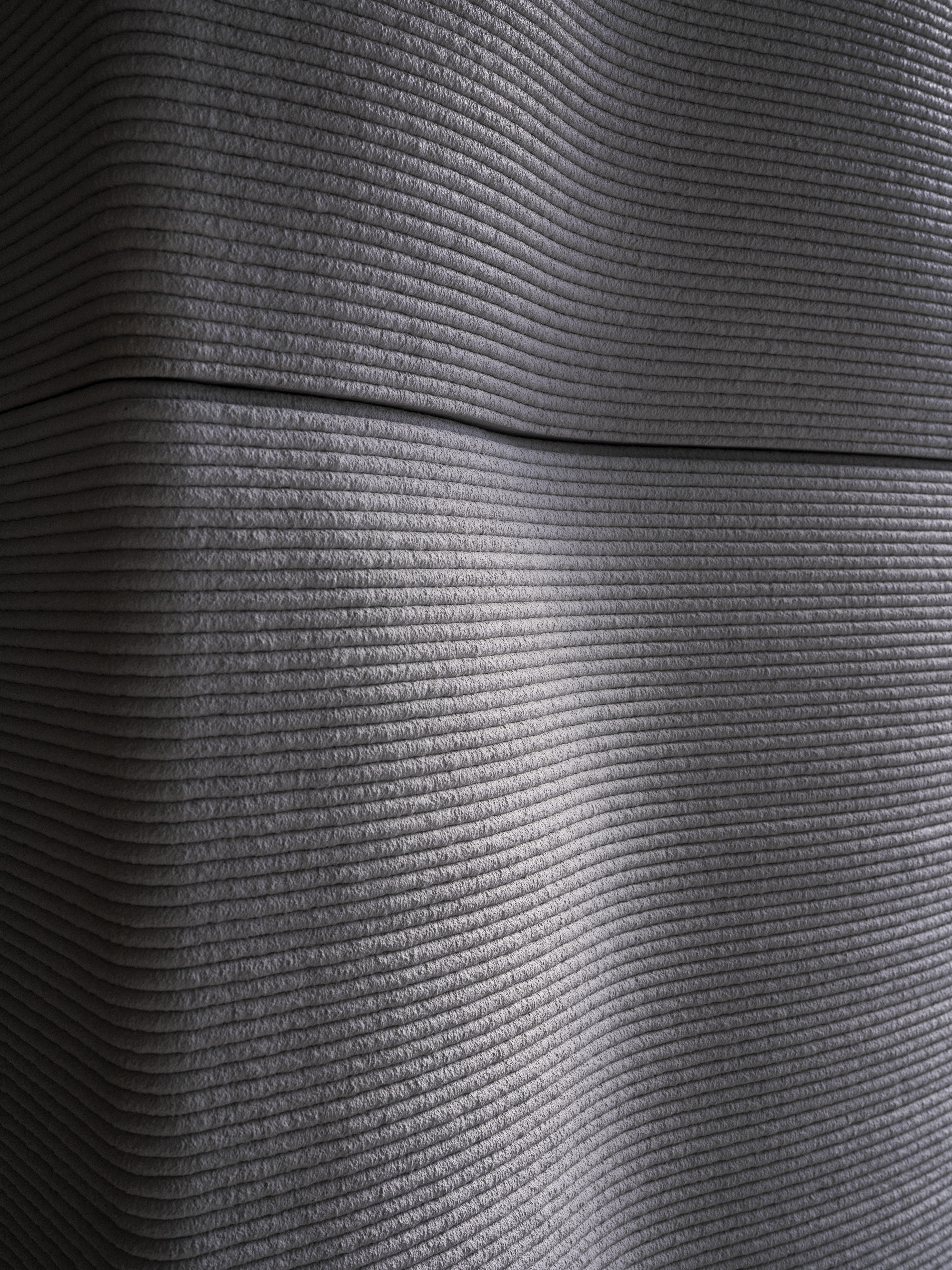 Horizontally striated concrete wall surface with recessed shadow line in raking light
