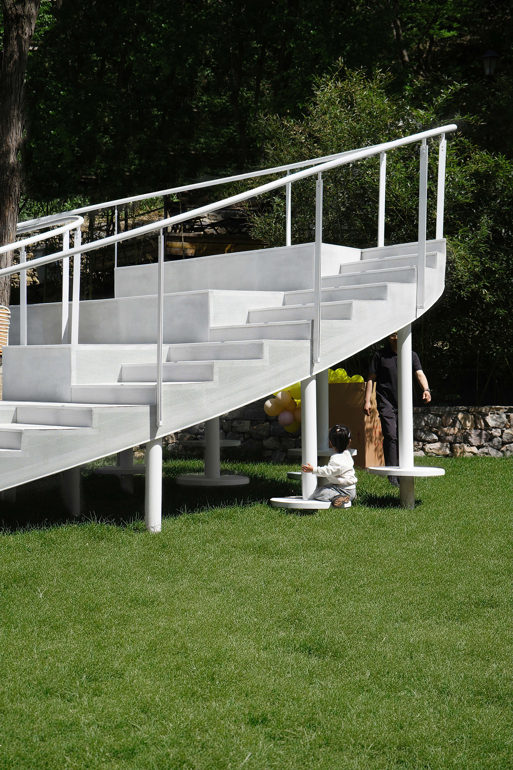 Side elevation of the elevated seating platform with children playing beneath in shade