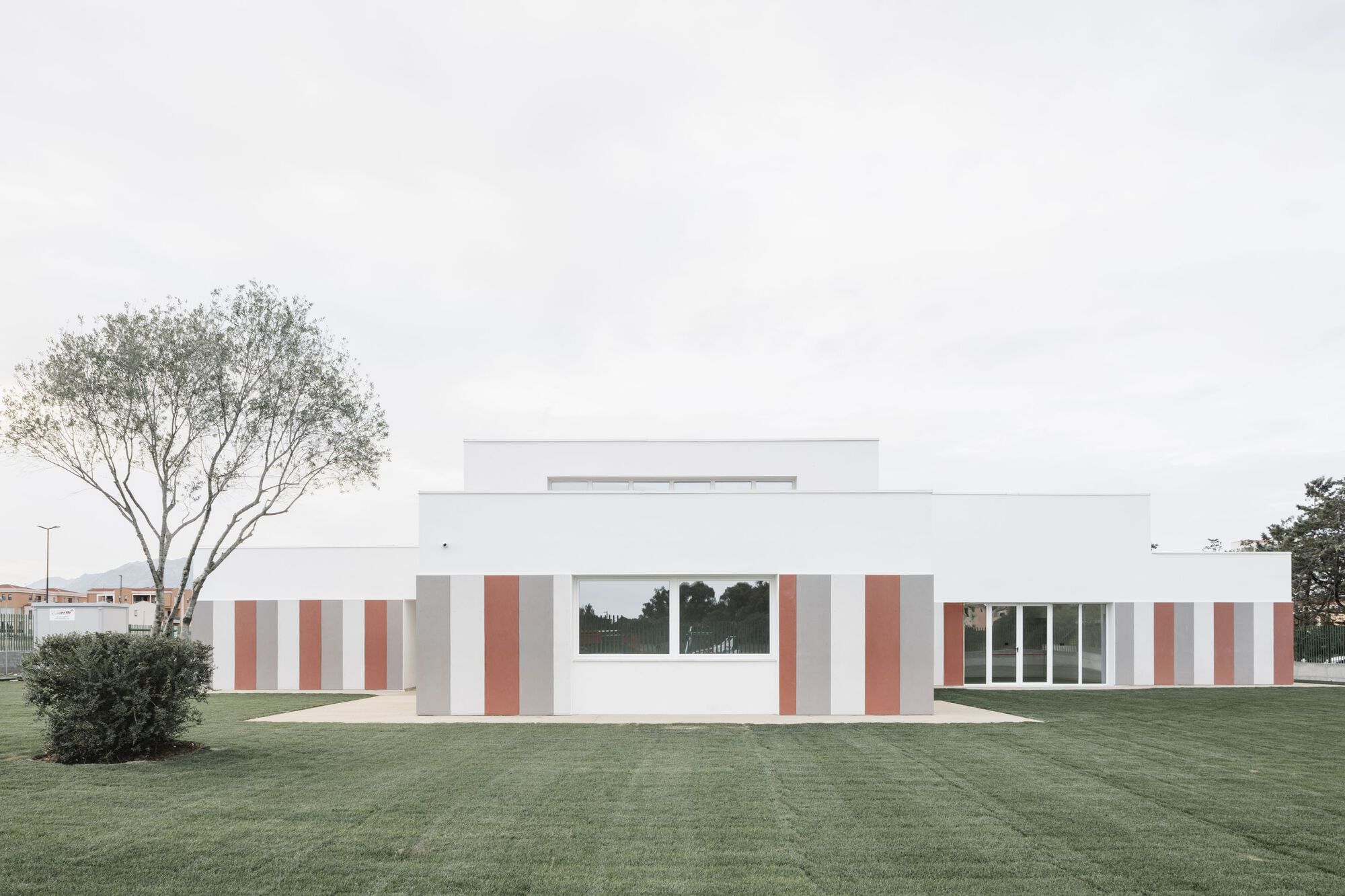Side elevation showing the staggered white volumes with terracotta panels and a tree at left