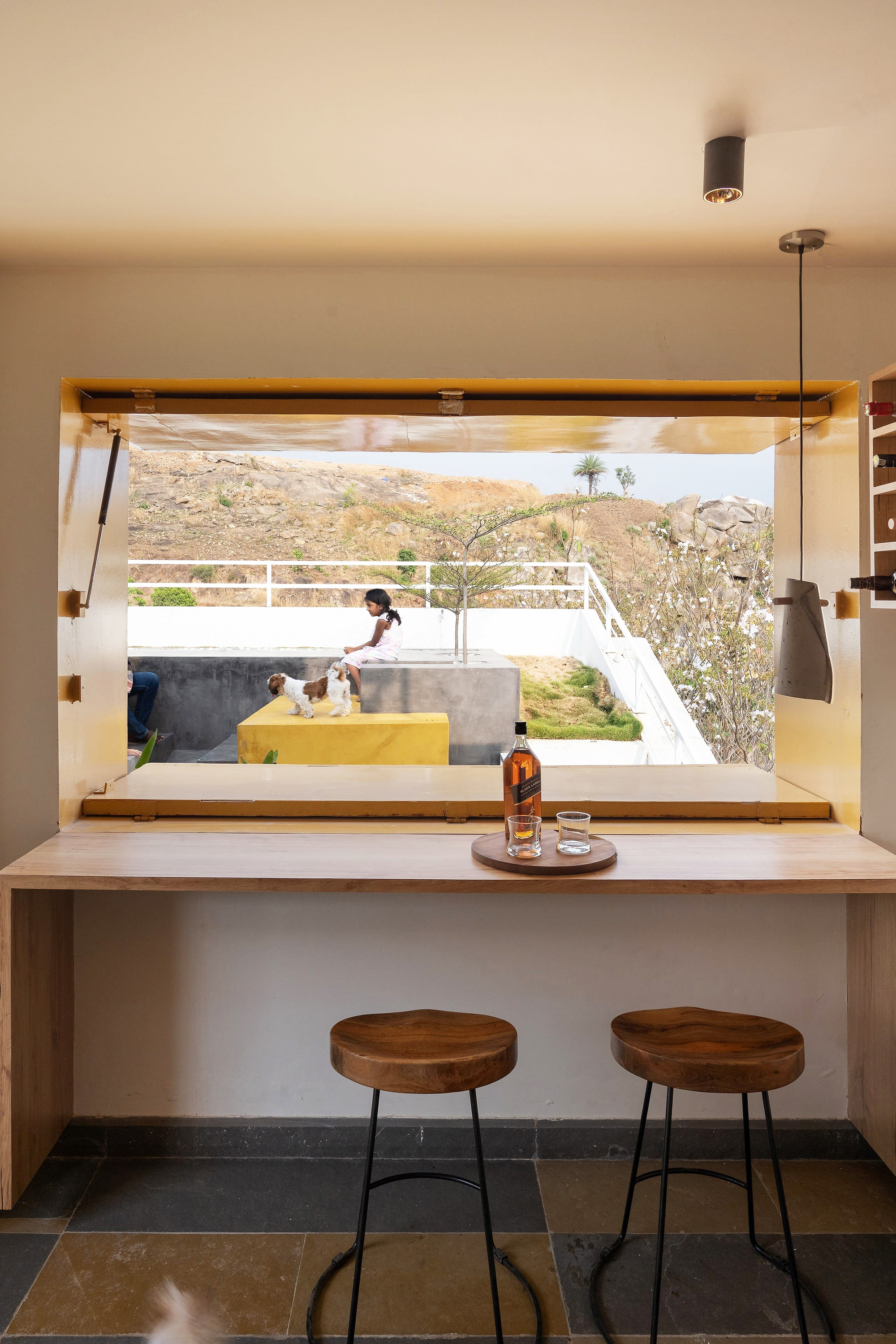 Built-in bench at window opening framing view of two figures on an exterior terrace