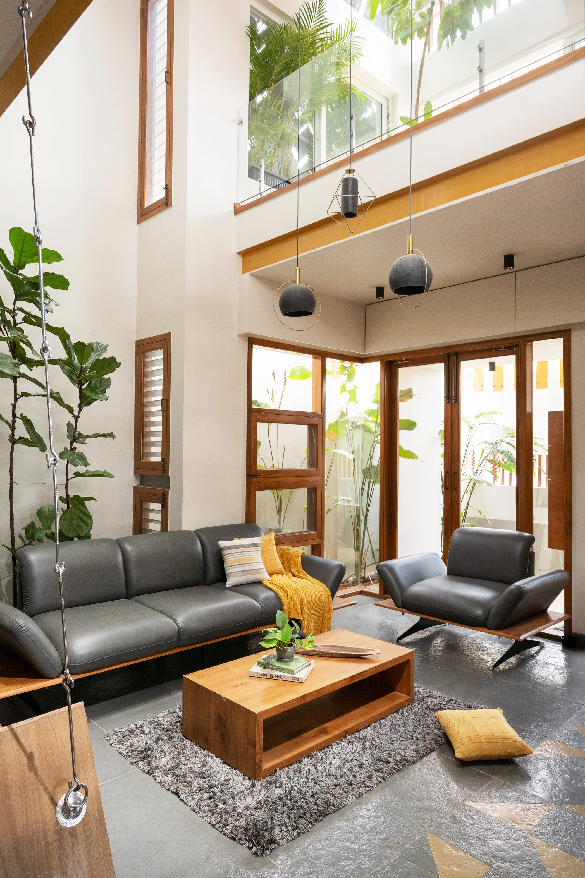 Double-height living room with timber-framed glazed doors opening to a courtyard with potted palms