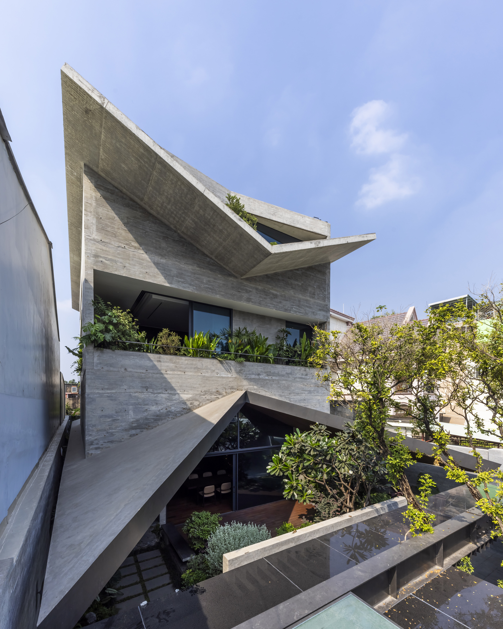 Angled view of the cantilevered concrete slabs with integrated planters and glazed openings below