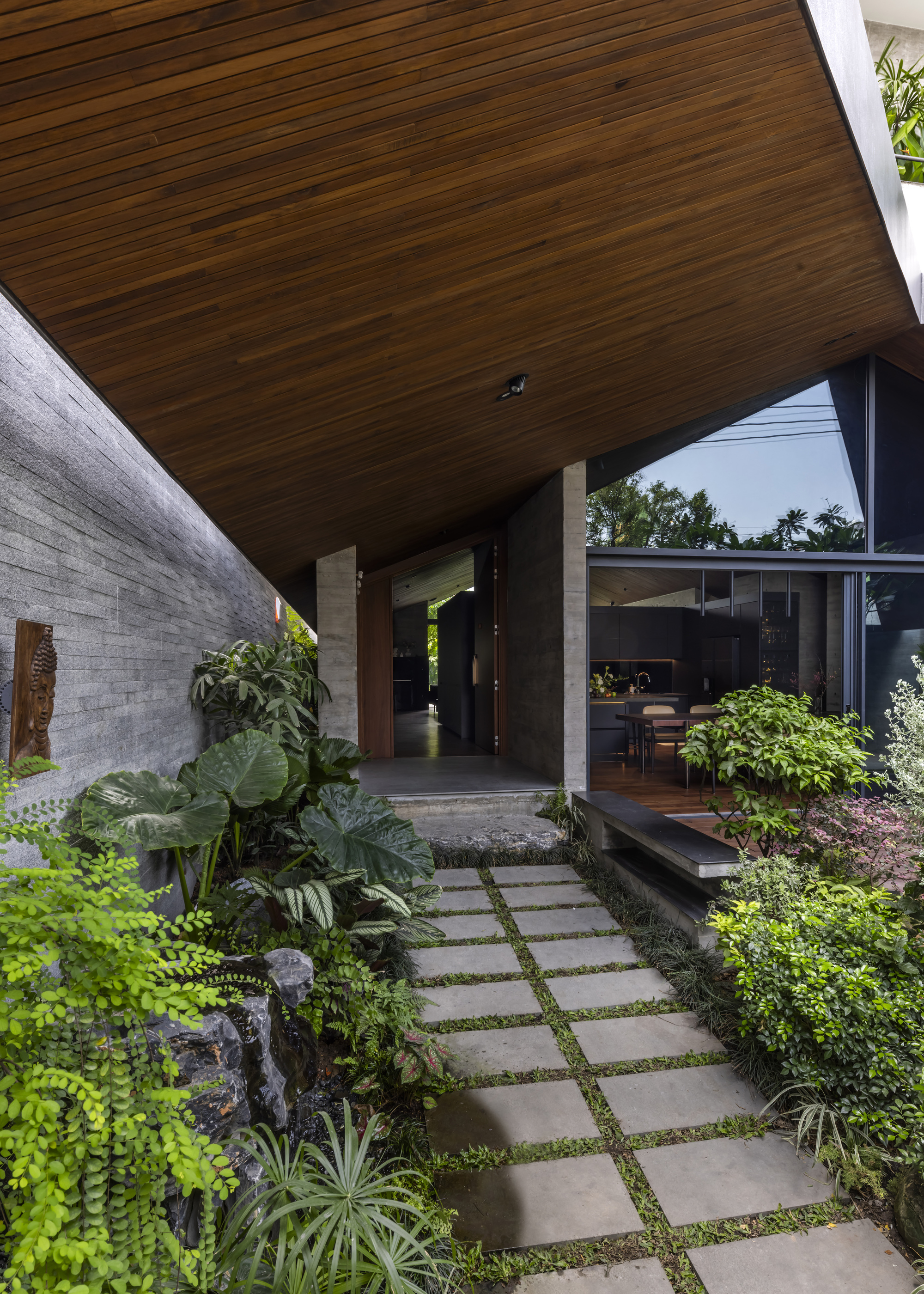 Entry courtyard with stepping stone path through planted beds under a timber-clad soffit