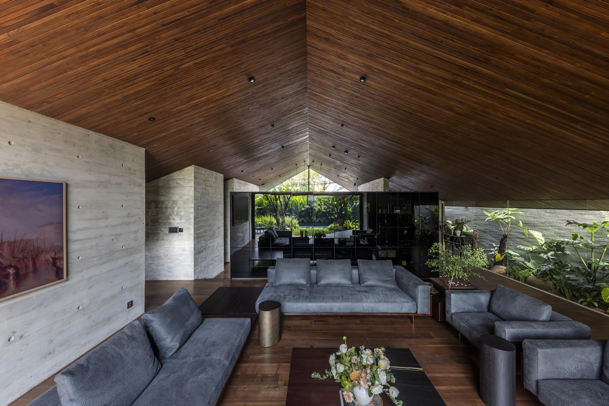 Living room with pitched timber ceiling and board-formed concrete walls framing a courtyard view