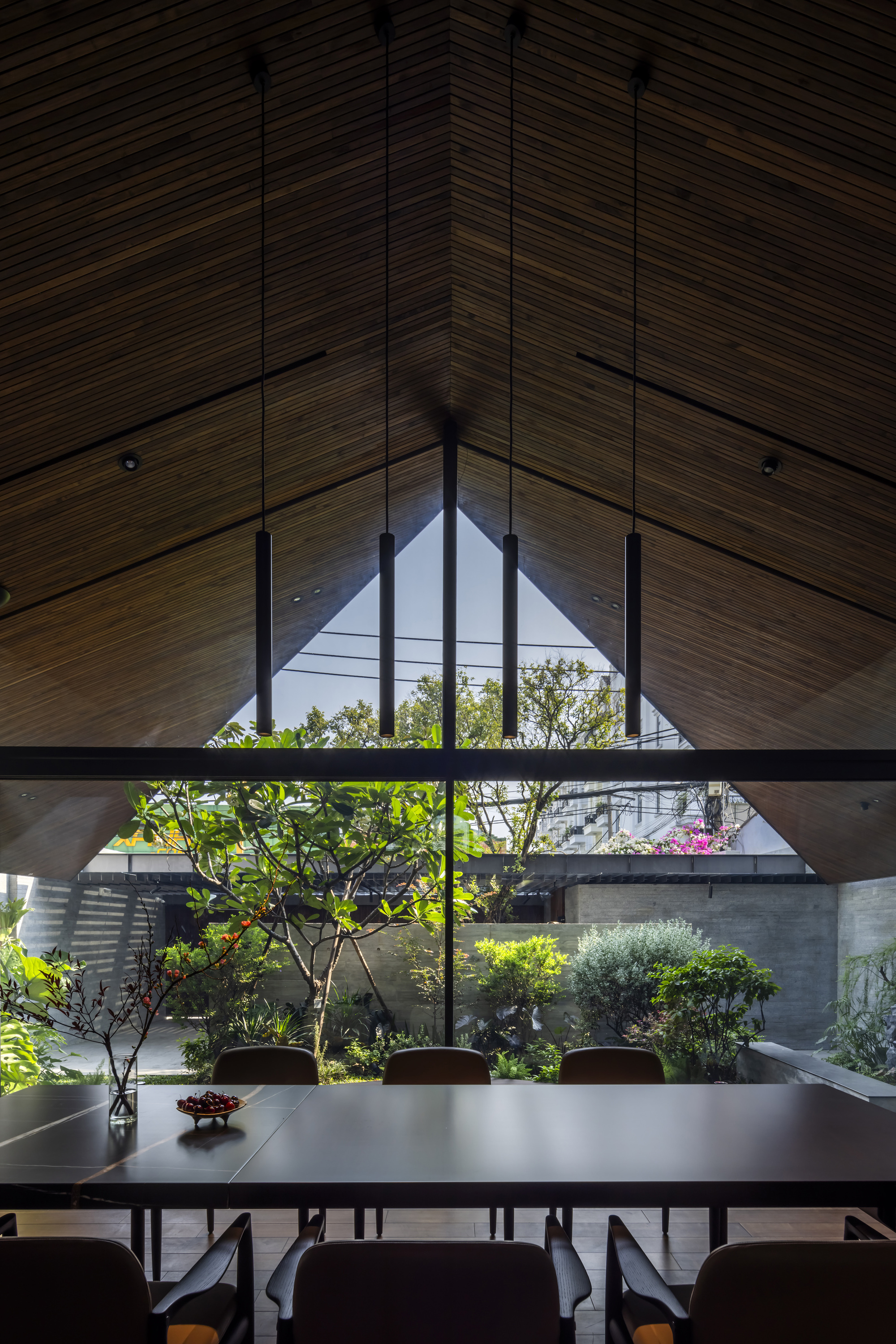 Dining table beneath gabled window overlooking an internal courtyard with trees and flowering plants