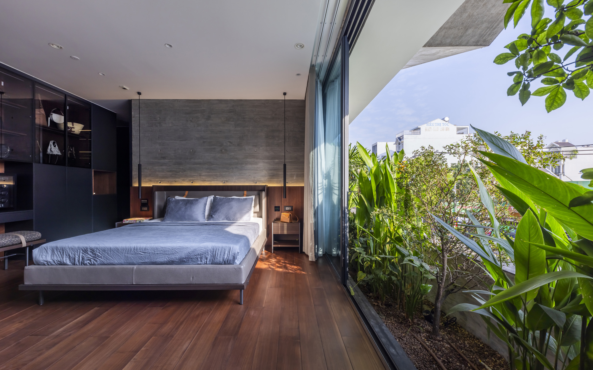 Bedroom with full-height glass doors opening to a planted terrace with tropical foliage