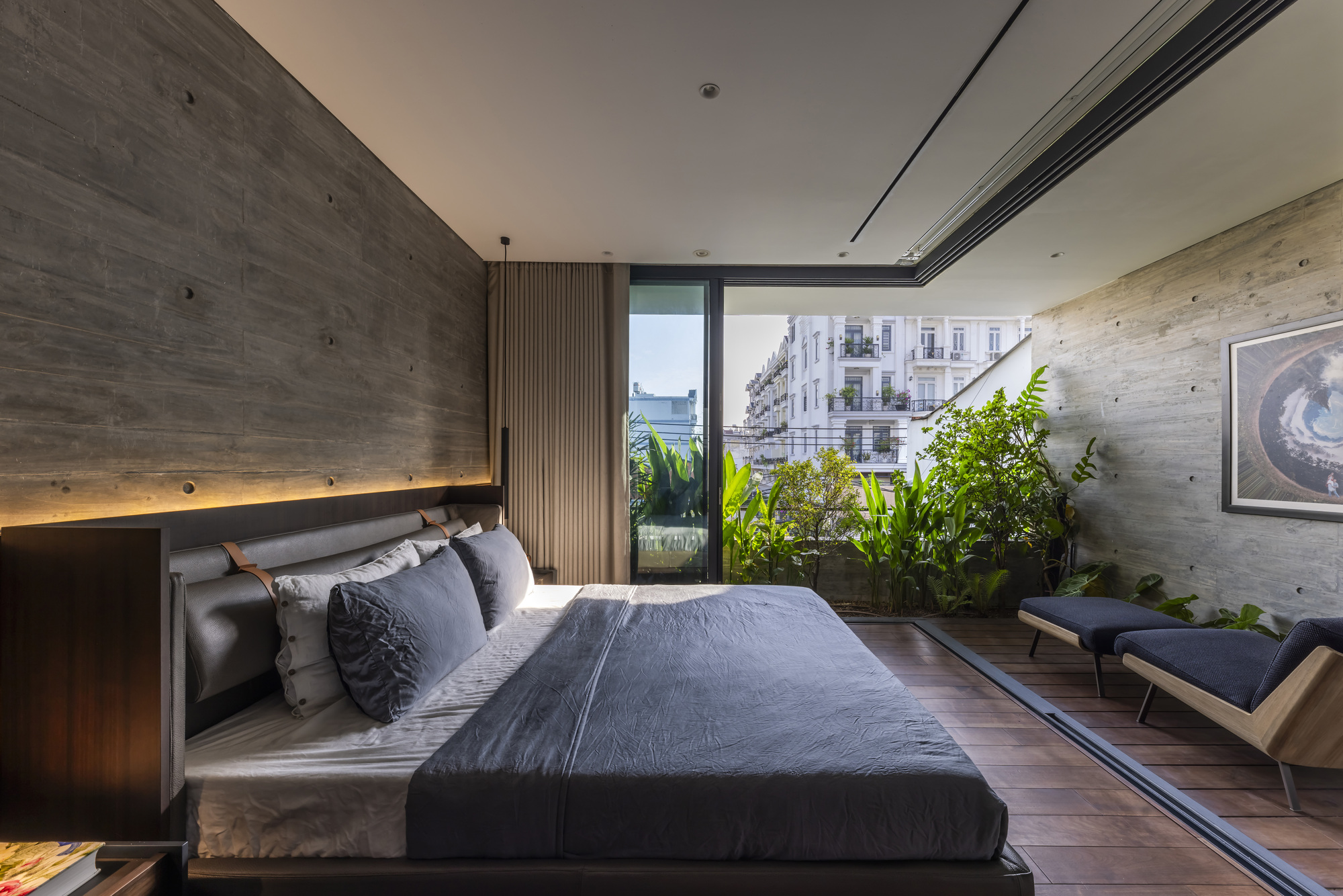 Bedroom with concrete accent wall and sliding doors framing a verdant balcony garden