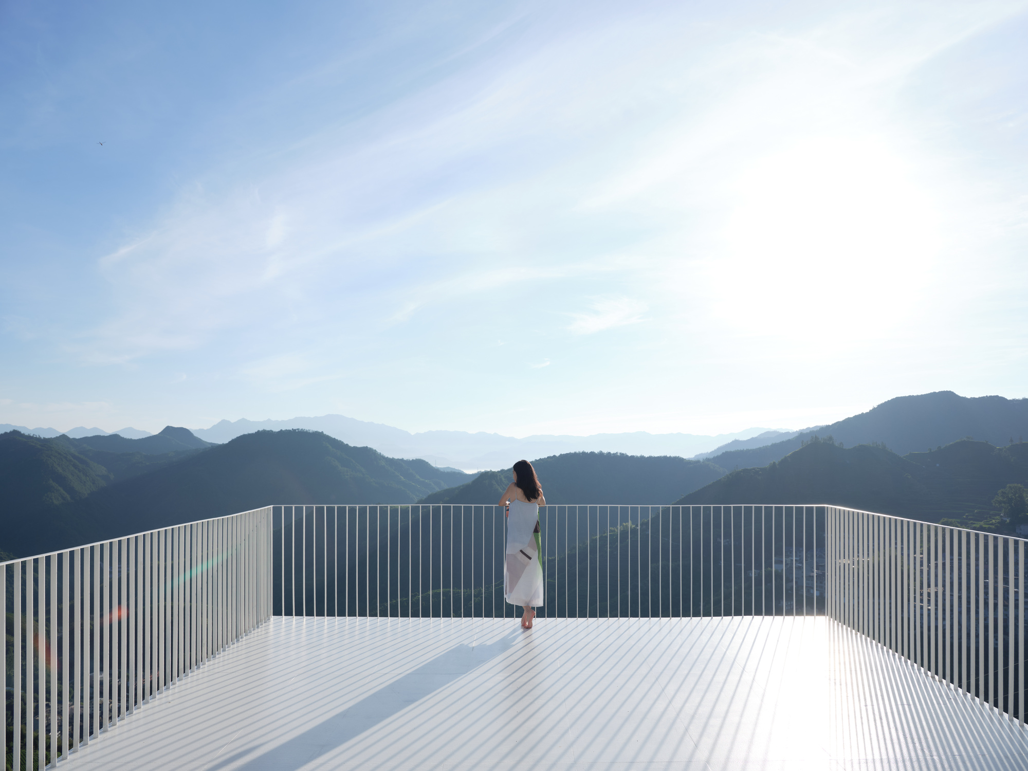 Rooftop terrace with vertical metal louvers overlooking a mountain range on a clear day