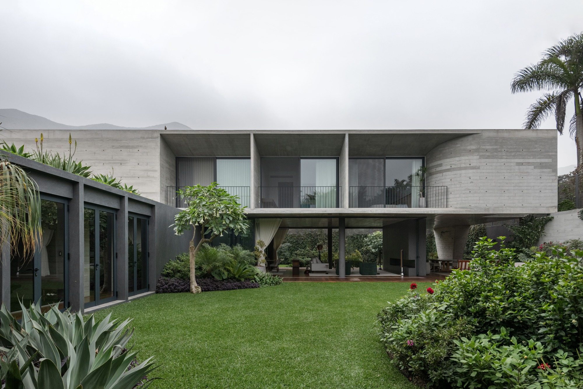Garden elevation showing the elevated concrete volume on pilotis with glazed openings overlooking the lawn