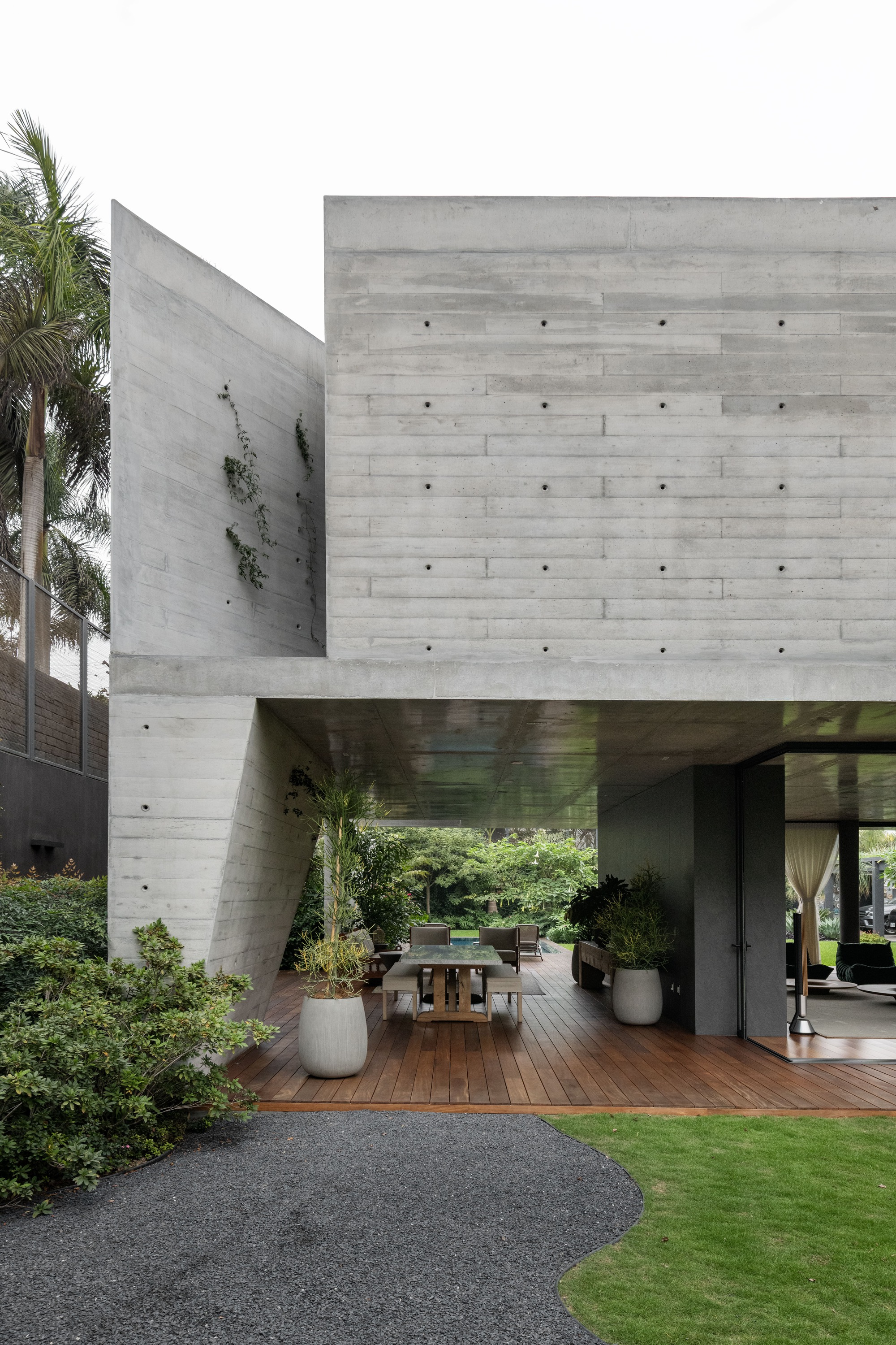 View of the cantilevered concrete masses sheltering the timber deck terrace with palm trees alongside