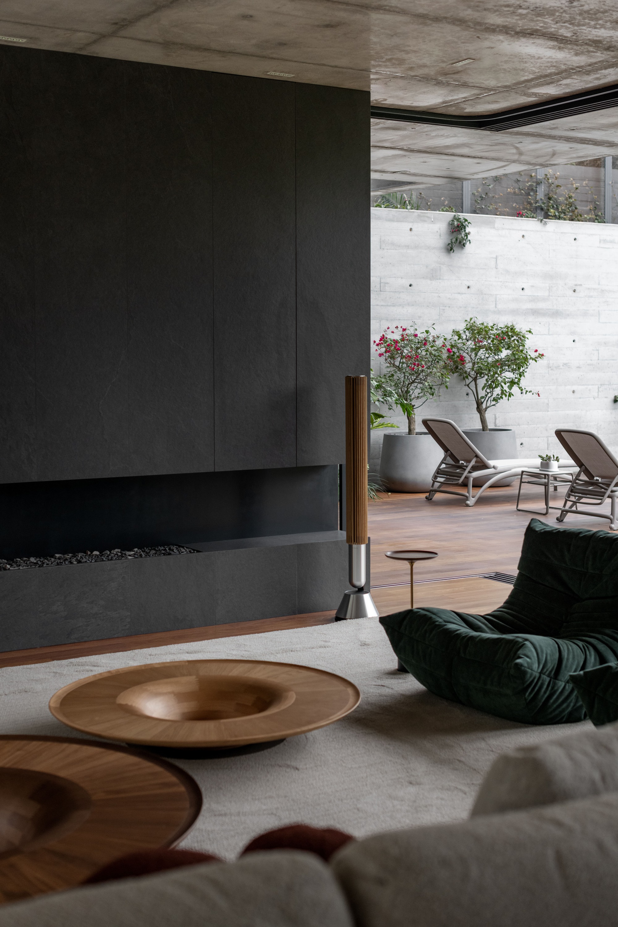 Living room with blackened steel fireplace wall overlooking a courtyard with lounge chairs