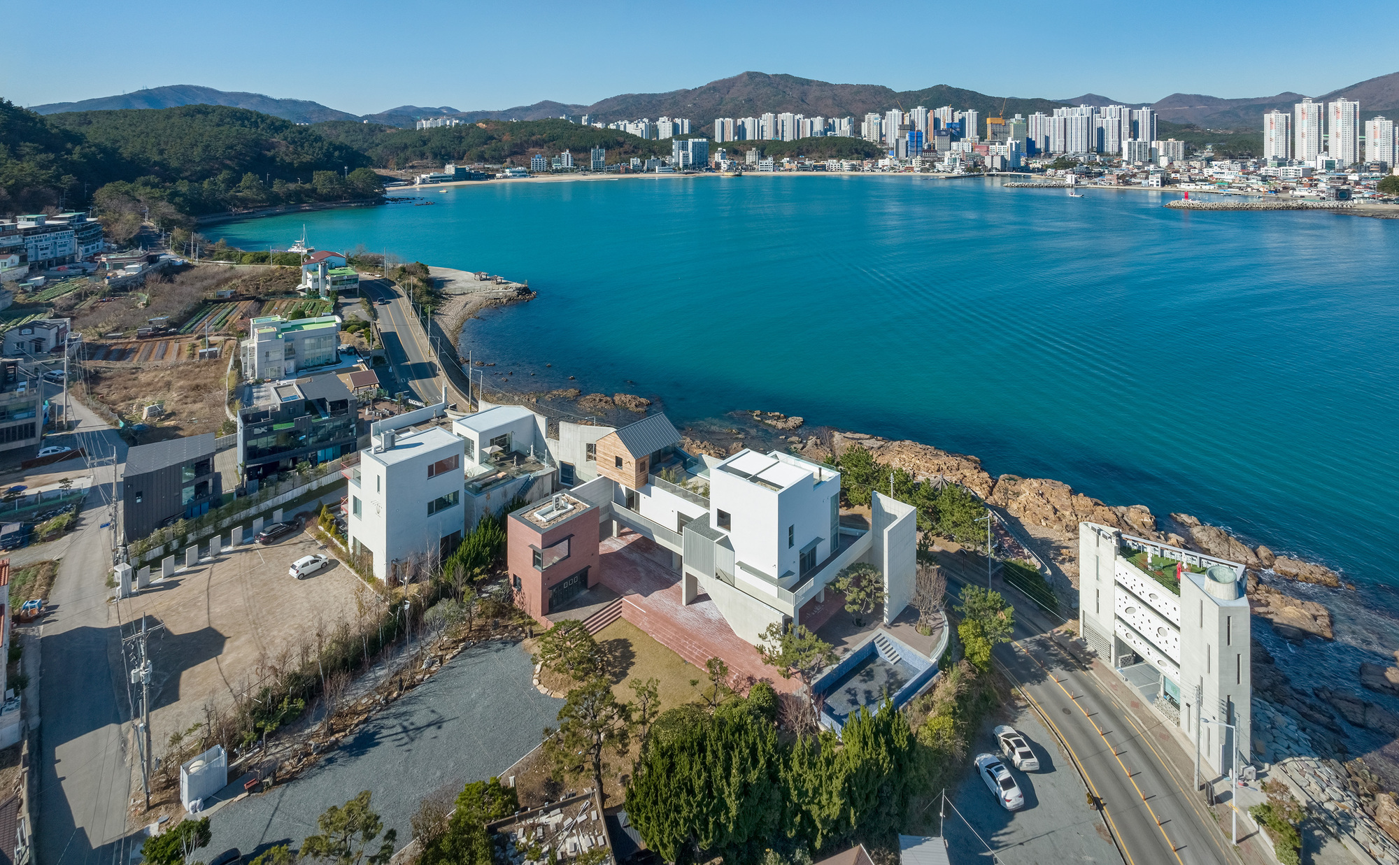 Aerial view of the residential cluster along the rocky shoreline with turquoise water and distant mountains