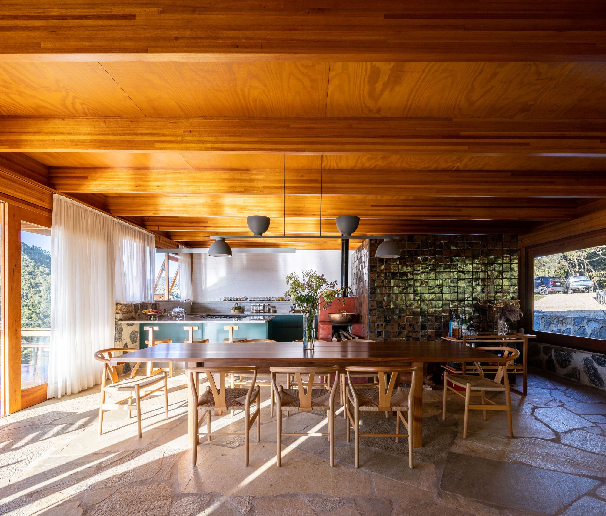 Dining area with timber ceiling beams and irregular stone floor illuminated by morning sunlight