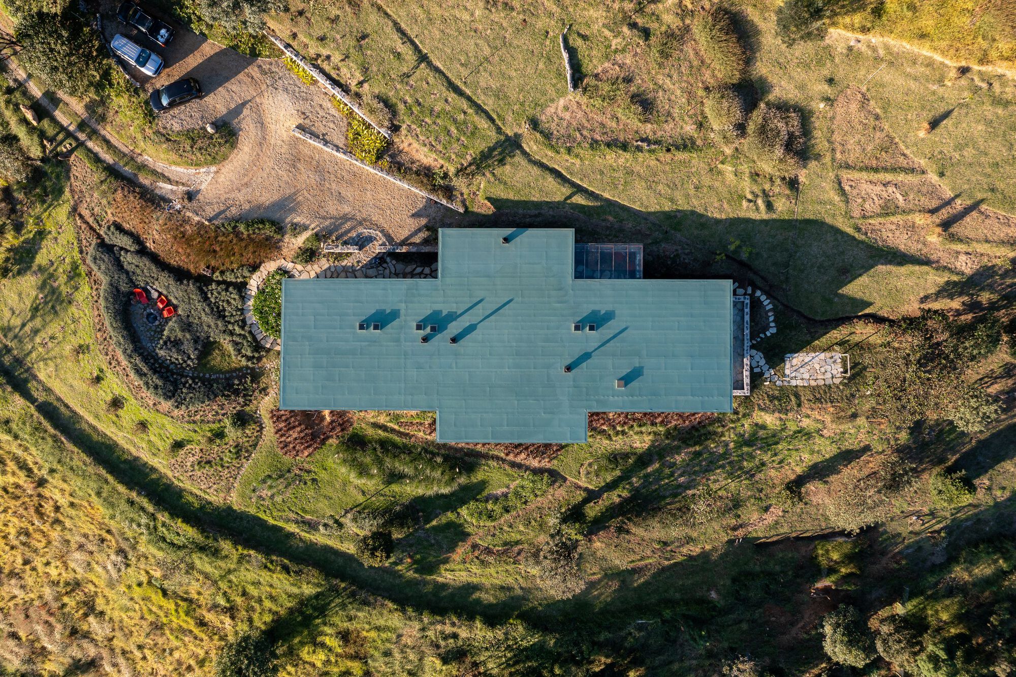 Overhead view of the gray metal roof with four skylights set into terraced hillside landscape