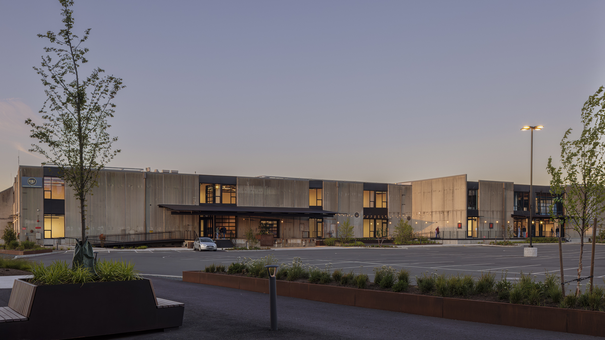 Long view of the corrugated metal facade across the parking lot at dusk