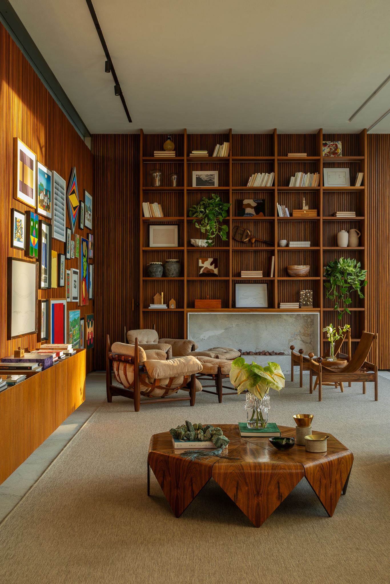 Living room with floor-to-ceiling timber shelving, gallery wall and sculptural wood coffee table