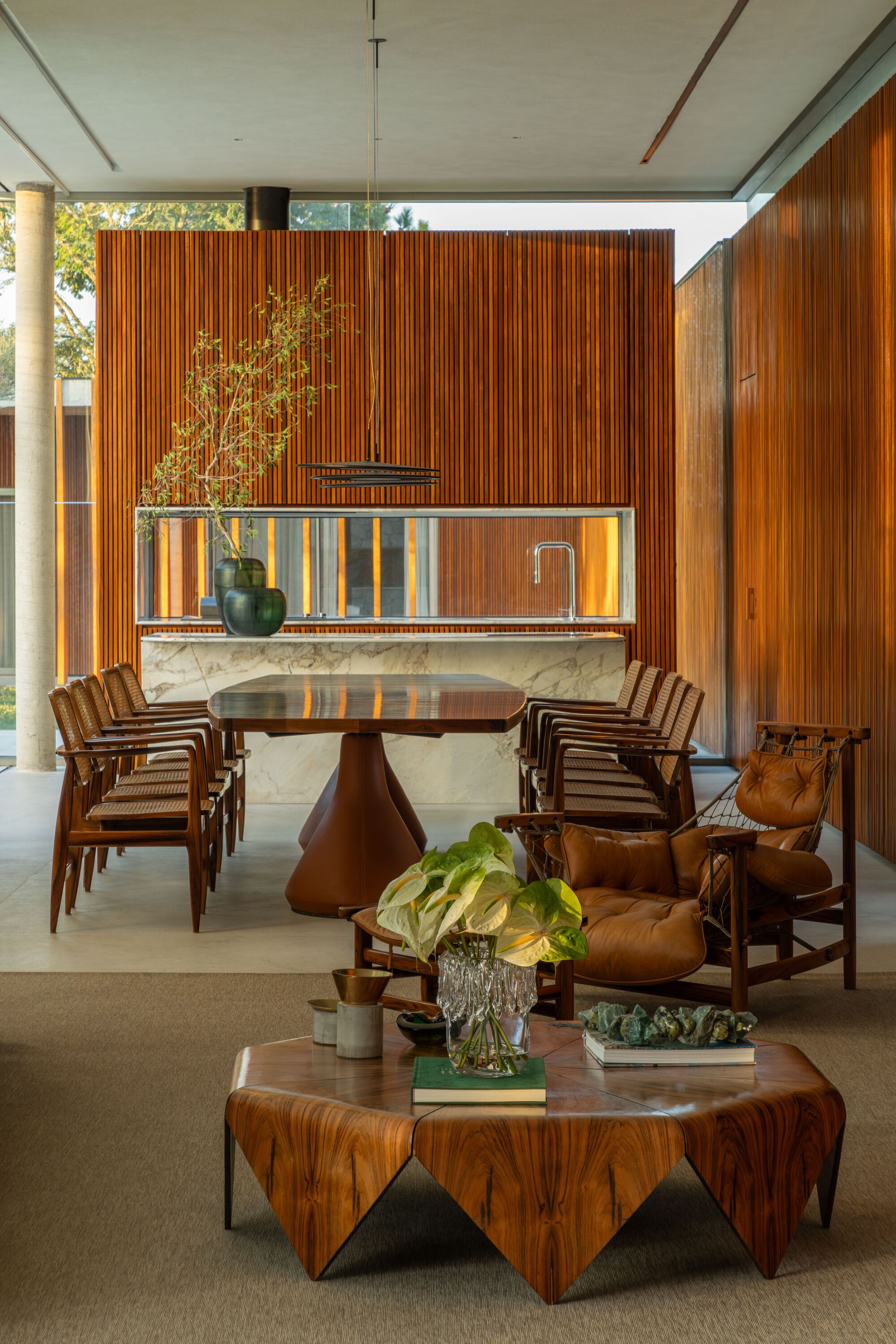 Dining area with illuminated marble-topped bar backed by vertical timber slats and foliage