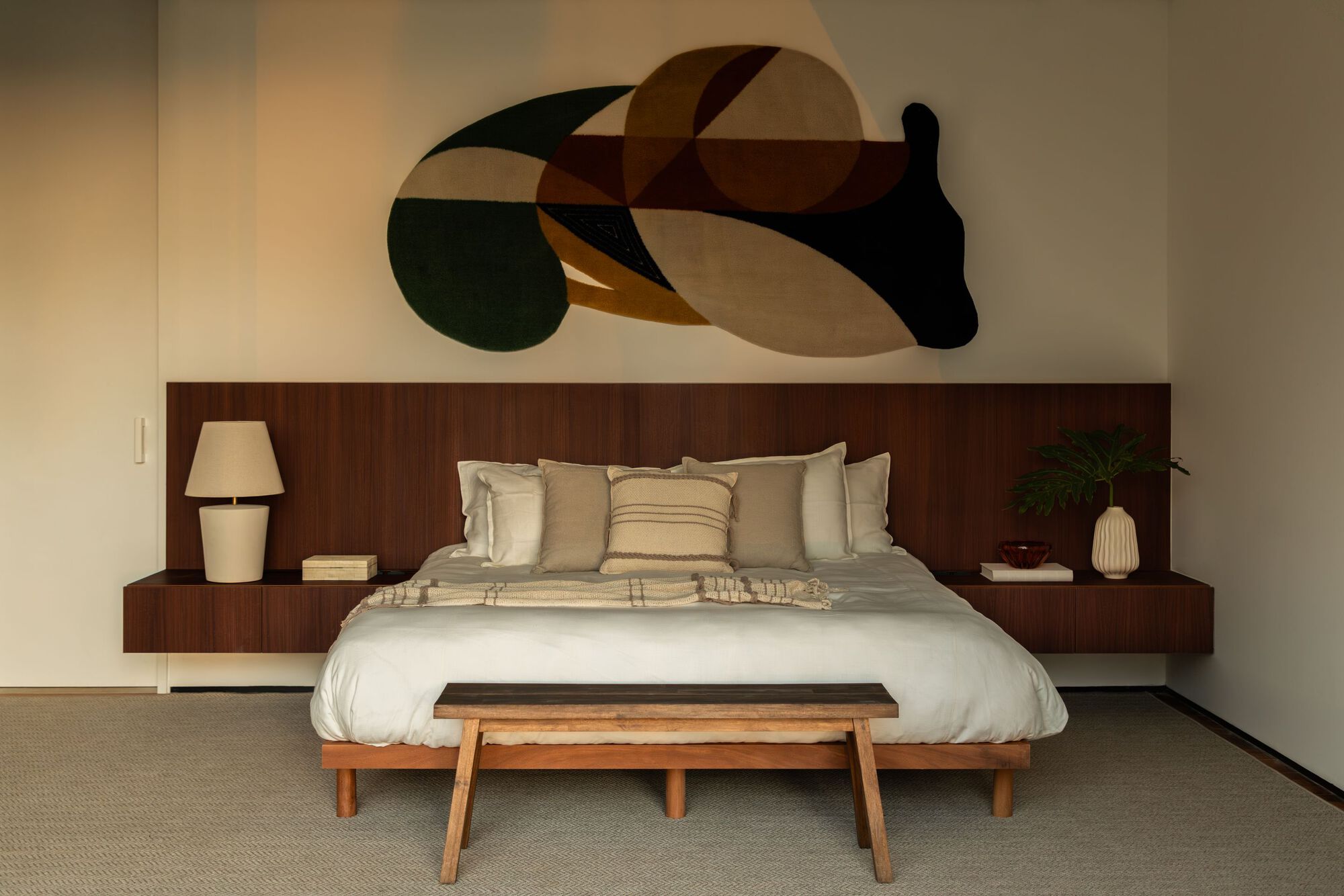 Bedroom with integrated timber headboard wall beneath a geometric abstract painting in warm tones