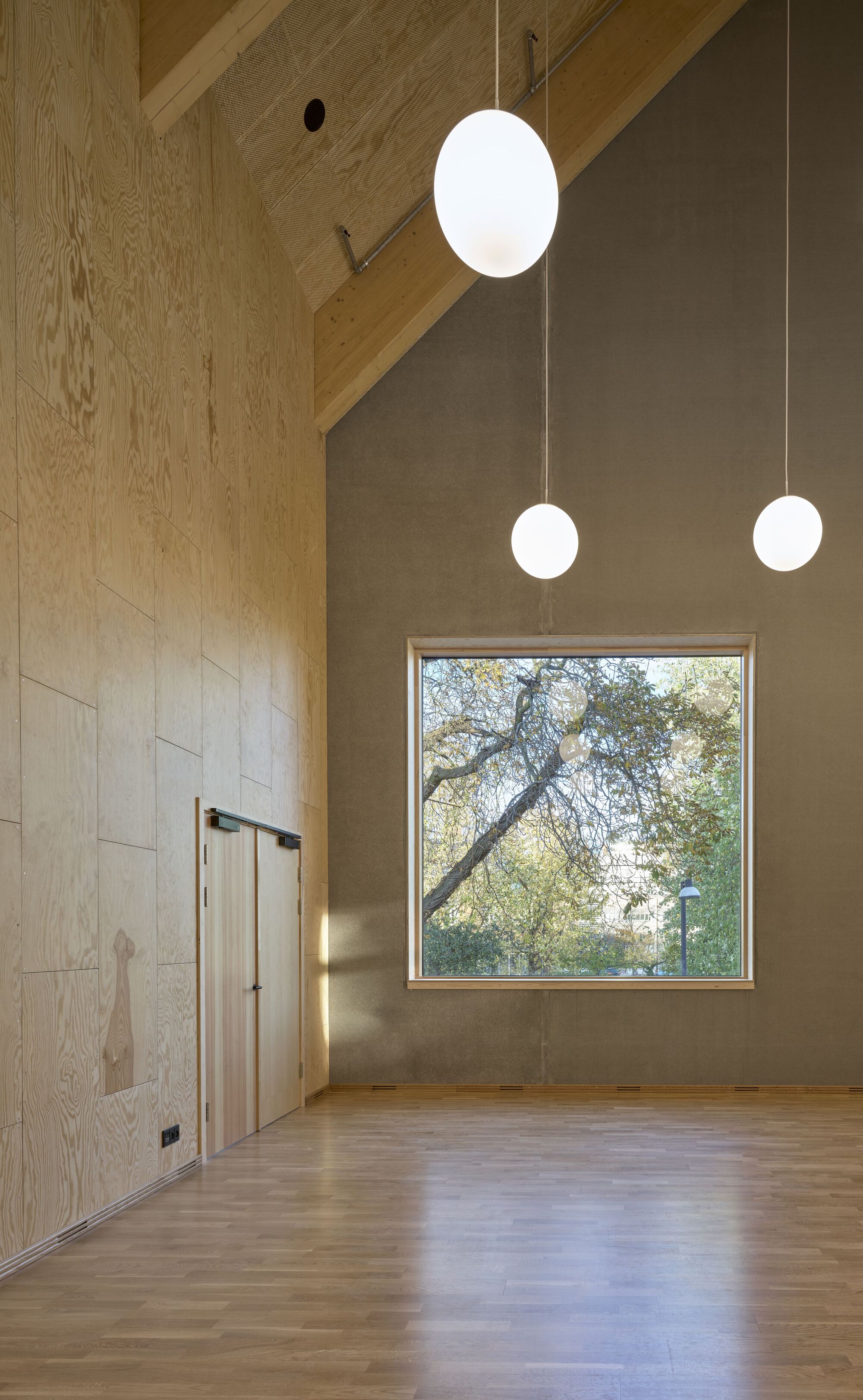 Double-height room with pendant lights and square window framing a bare tree outside