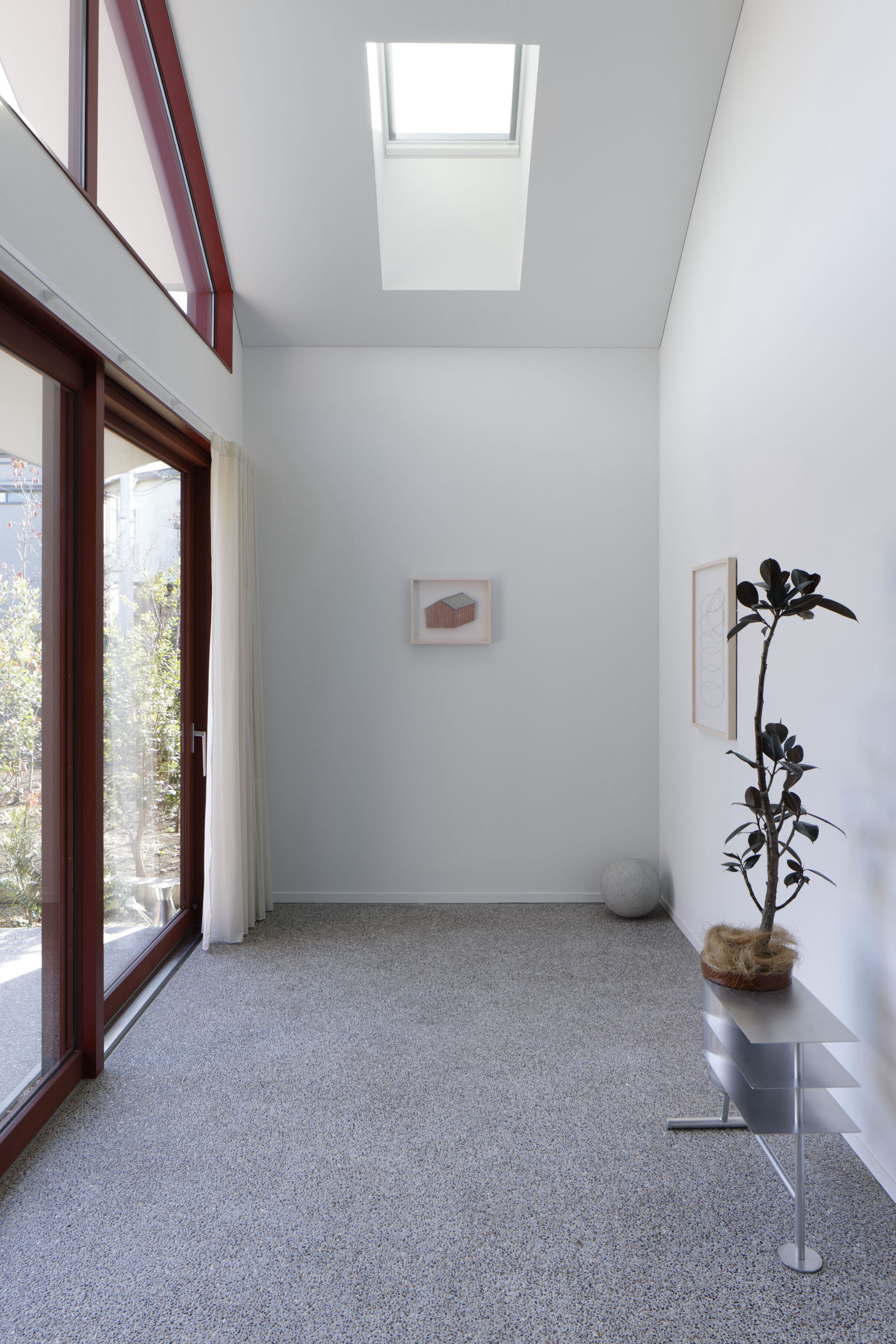 Double-height entry hall with terrazzo floor and skylight above a mahogany-framed glass door