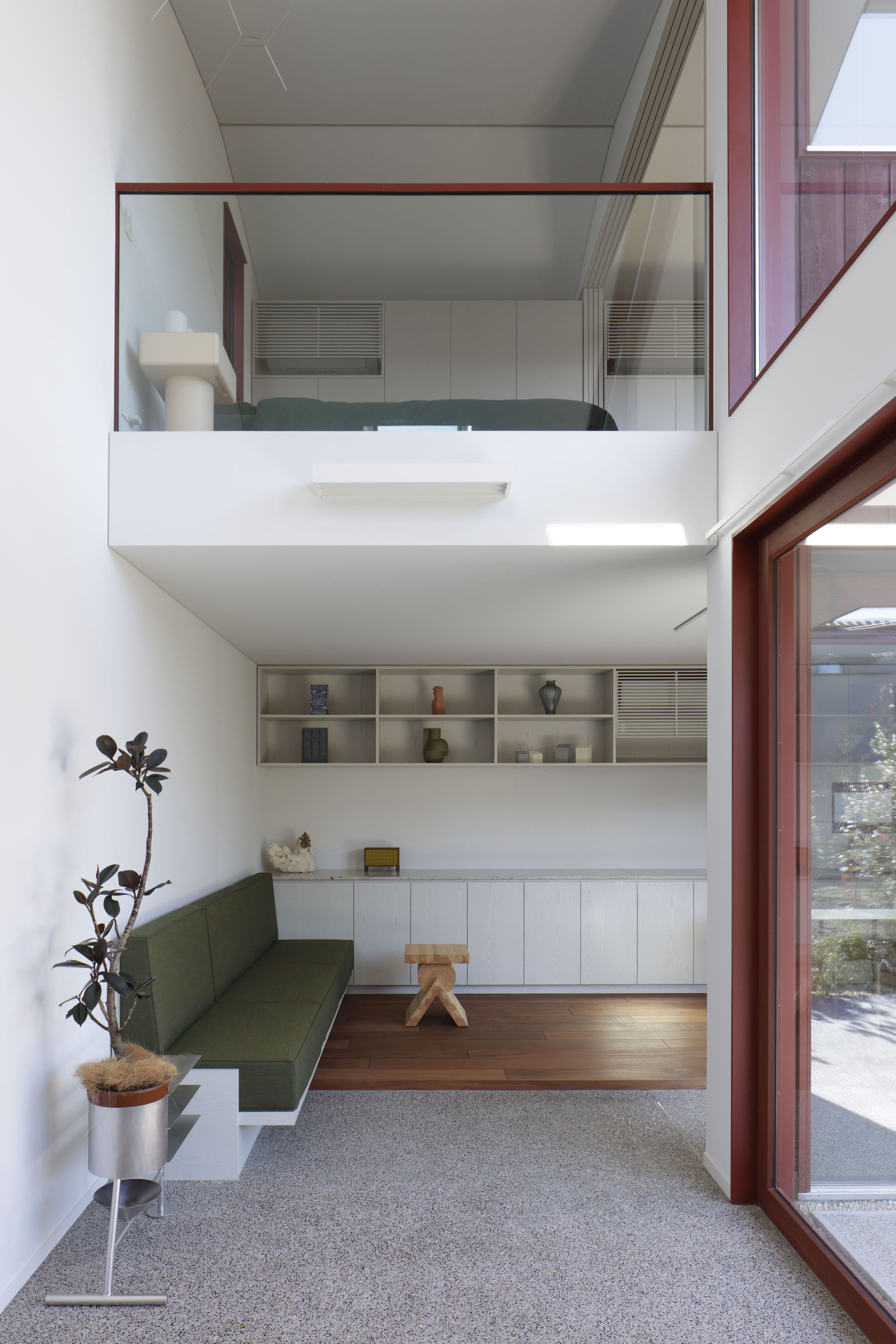 Double-height living space with mezzanine study overlooking built-in seating and open shelving below