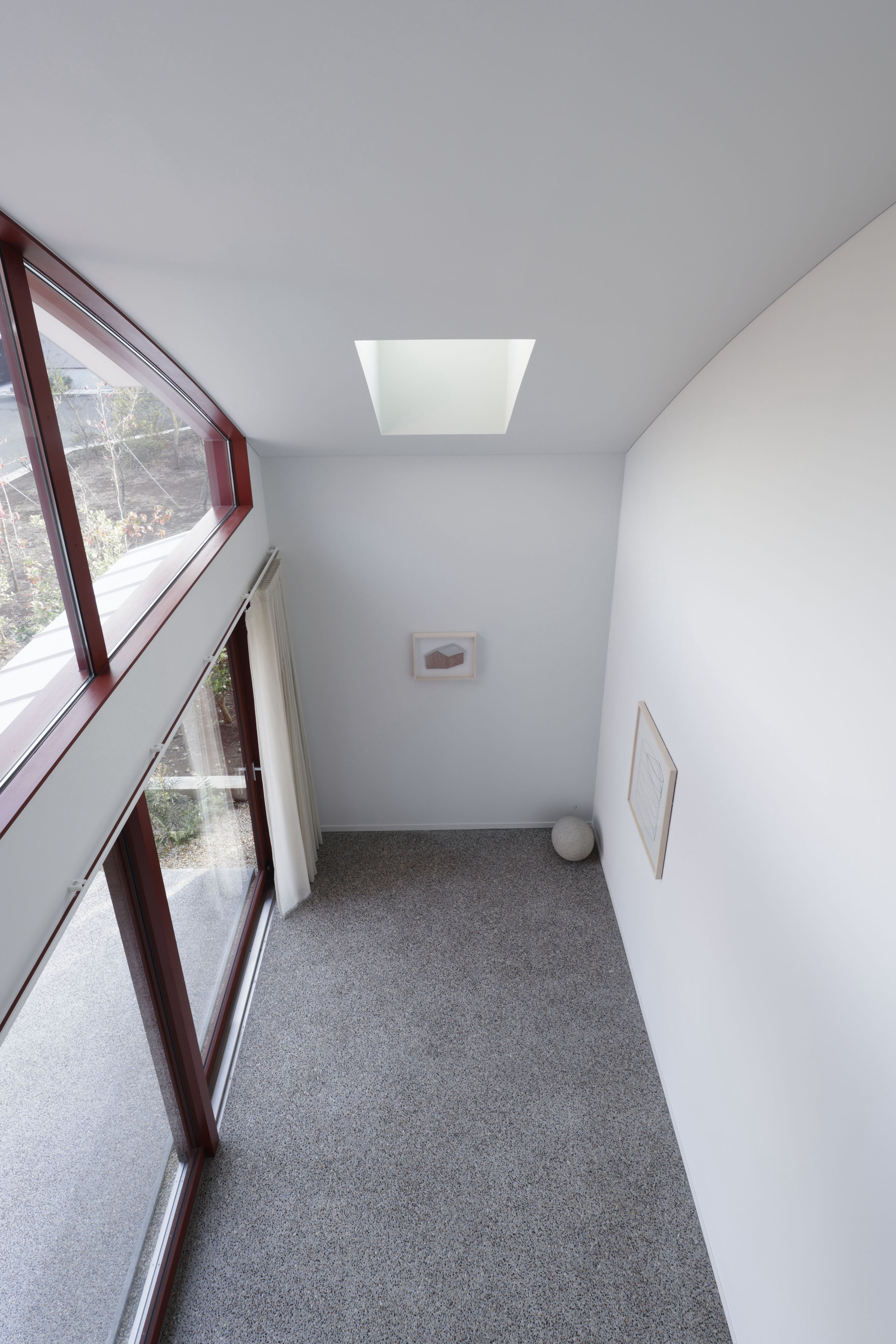 Narrow hallway with angled glazing, terrazzo flooring, white walls and central skylight above