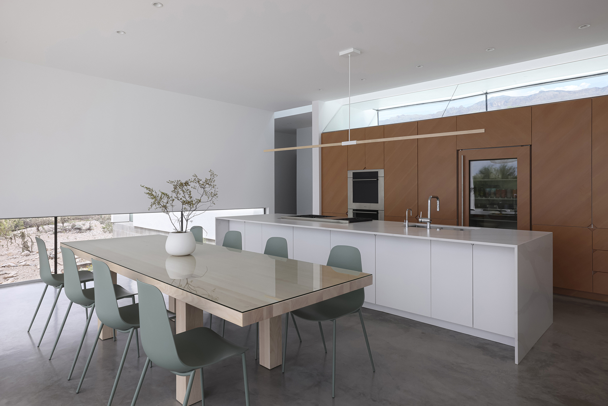 Kitchen and dining area with white island, sage chairs, and walnut-toned cabinetry wall
