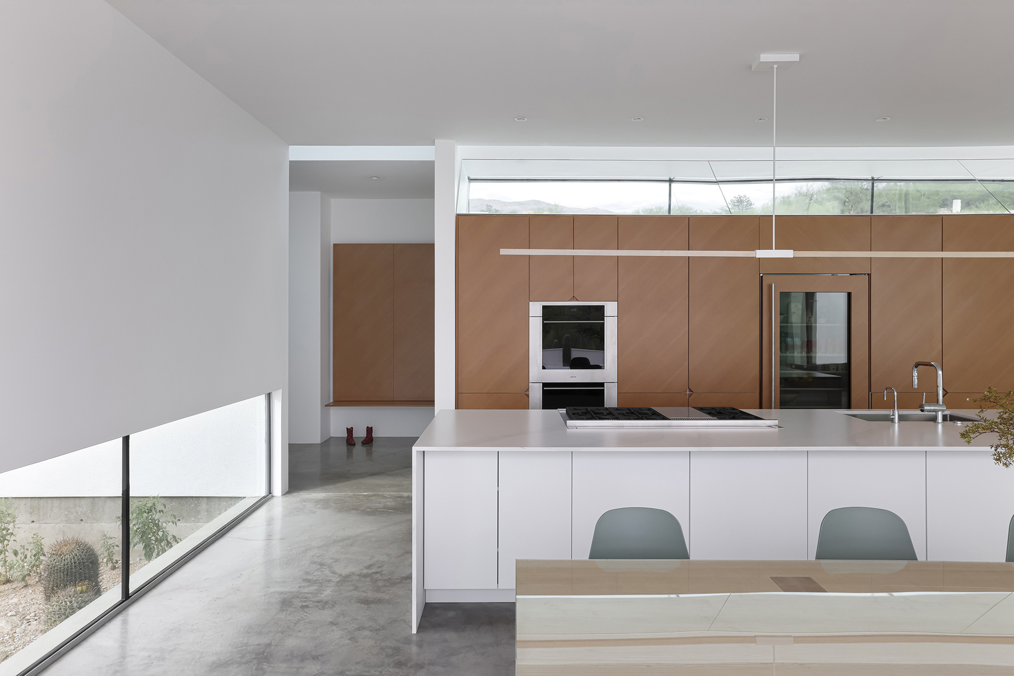 Kitchen island with polished white countertop and linear pendant light above clerestory windows