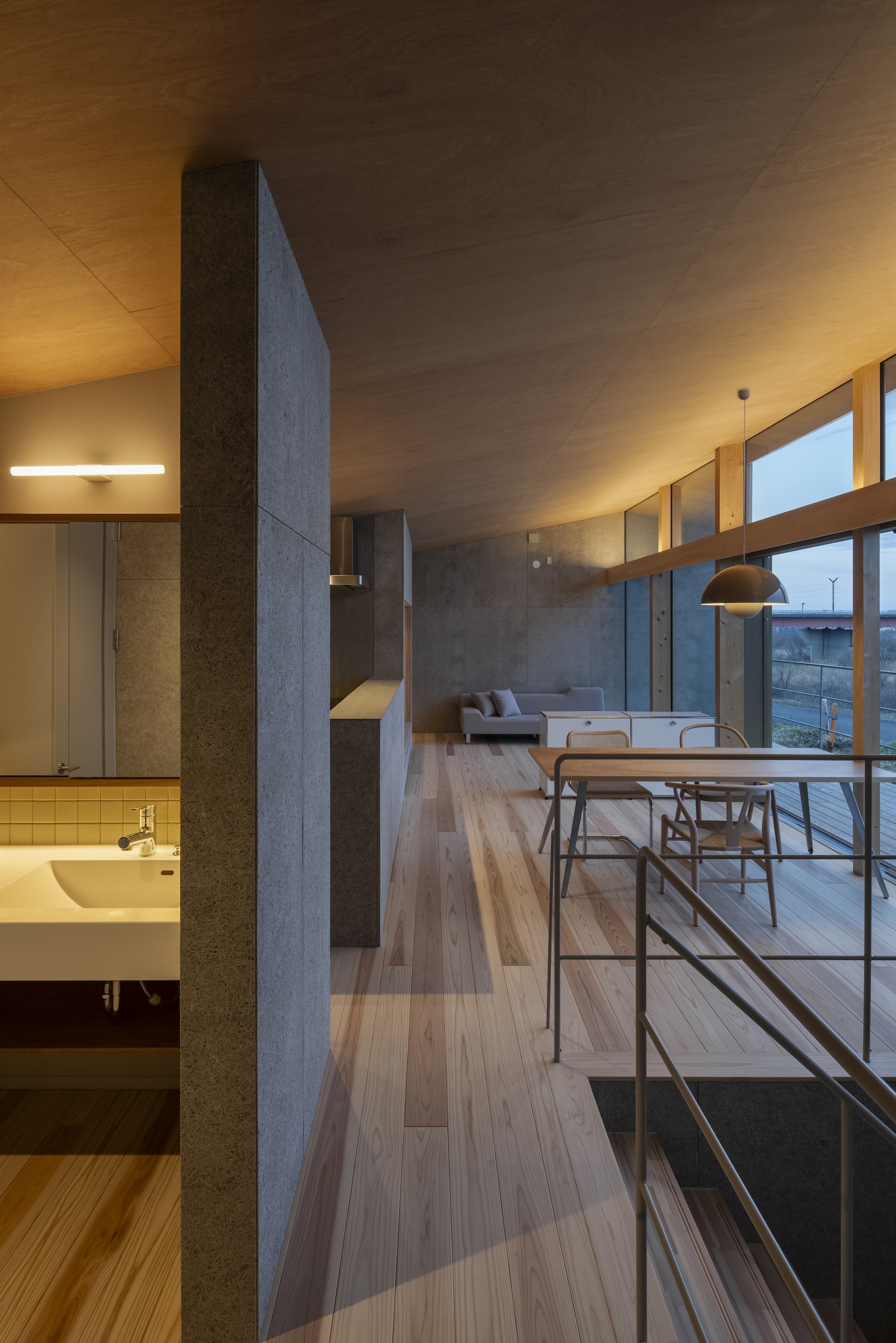 Upper-level corridor with metal railing overlooking the main living area and bathroom below