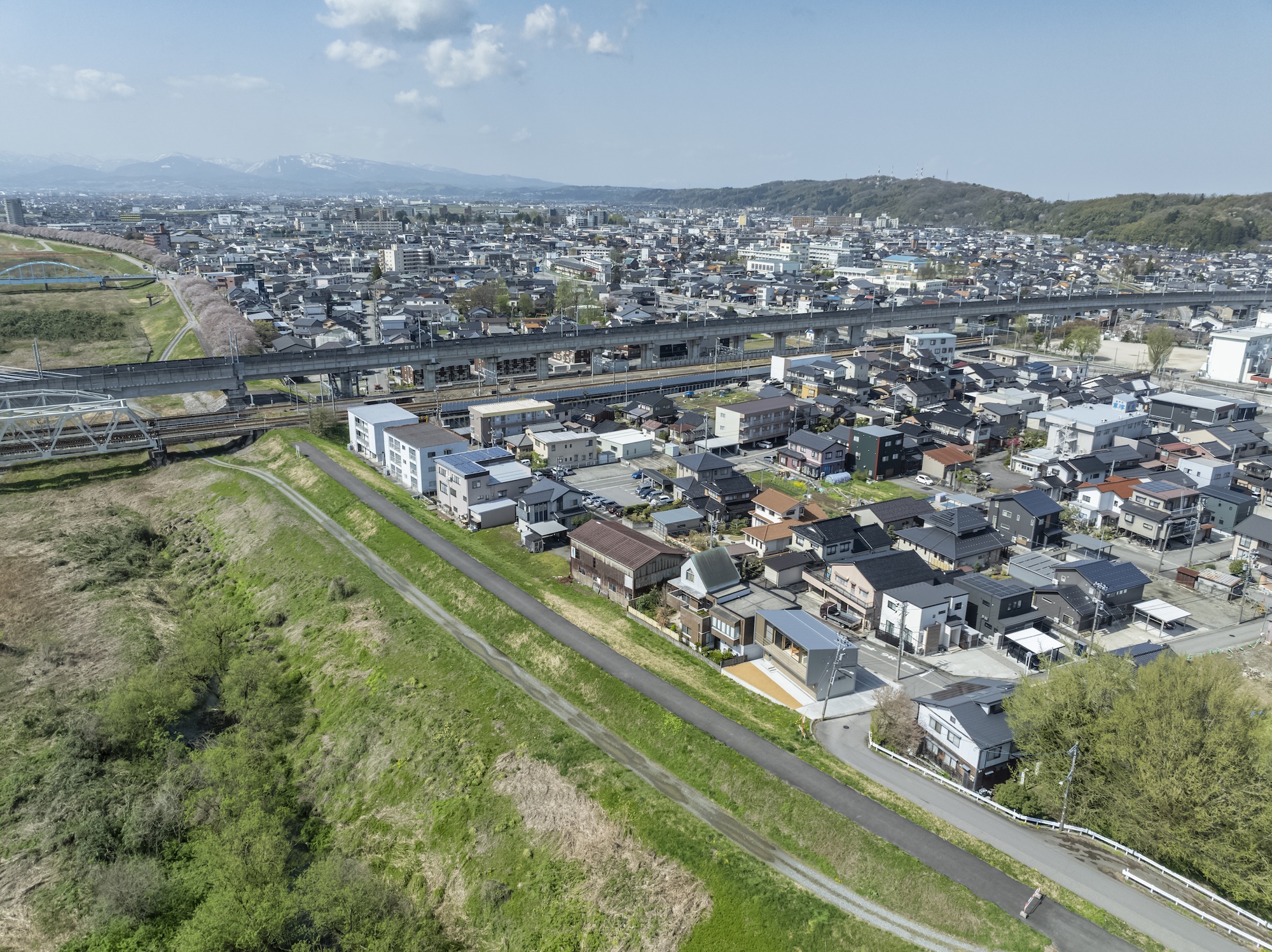 Aerial view of residential neighborhood with elevated highway and distant mountains under clear skies