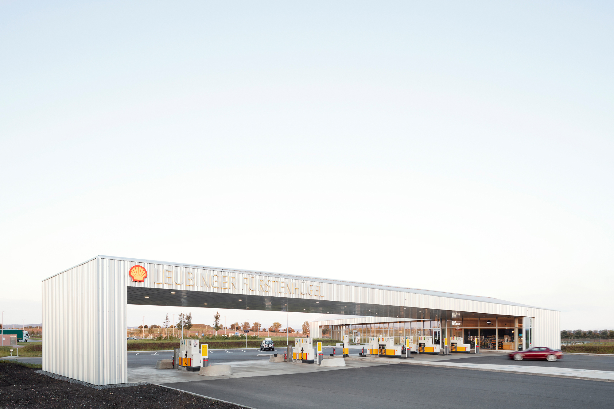 White corrugated metal canopy over fuel pumps at a service station in flat farmland