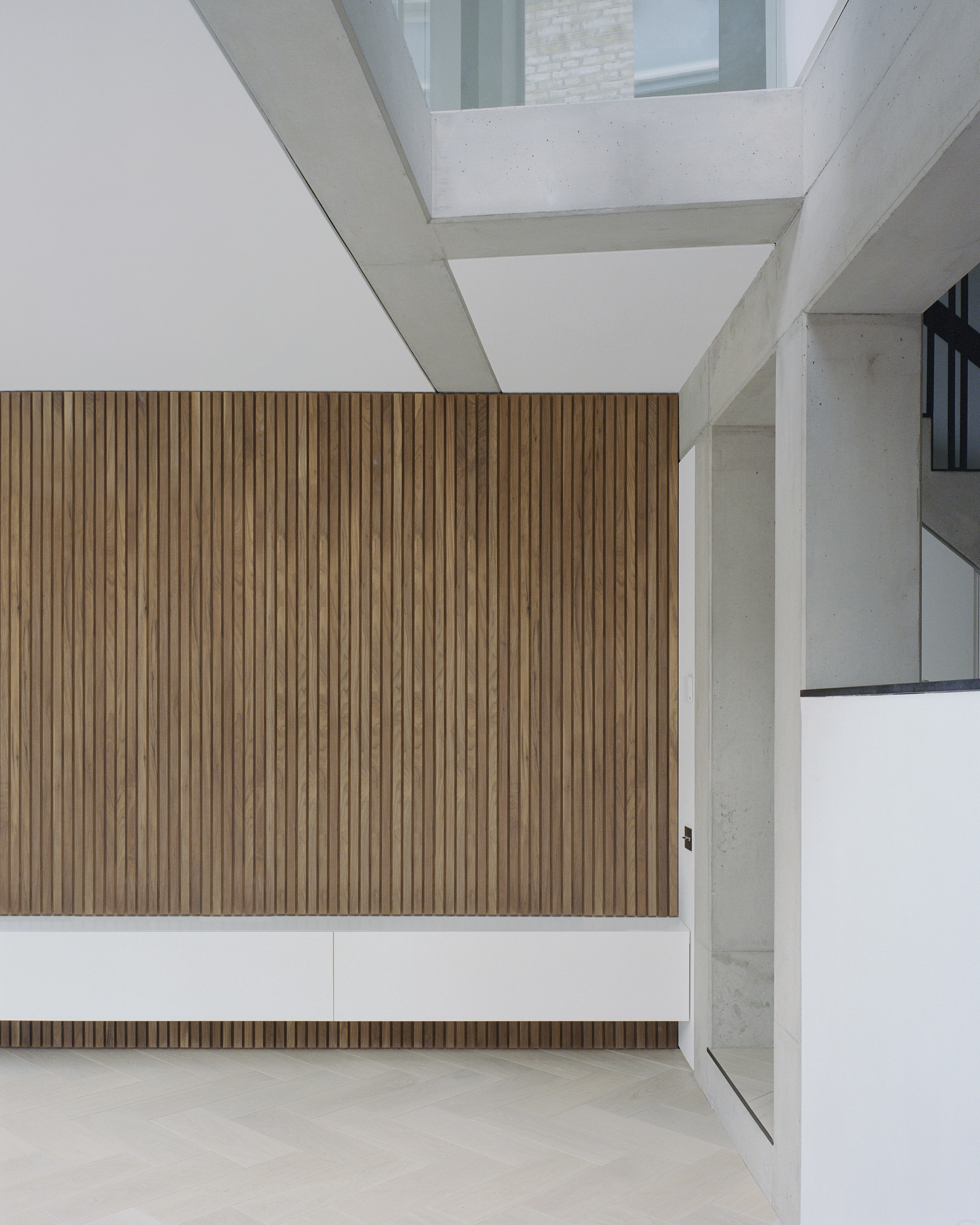 Top-down view of vertical timber slat wall with exposed concrete beams and skylight above