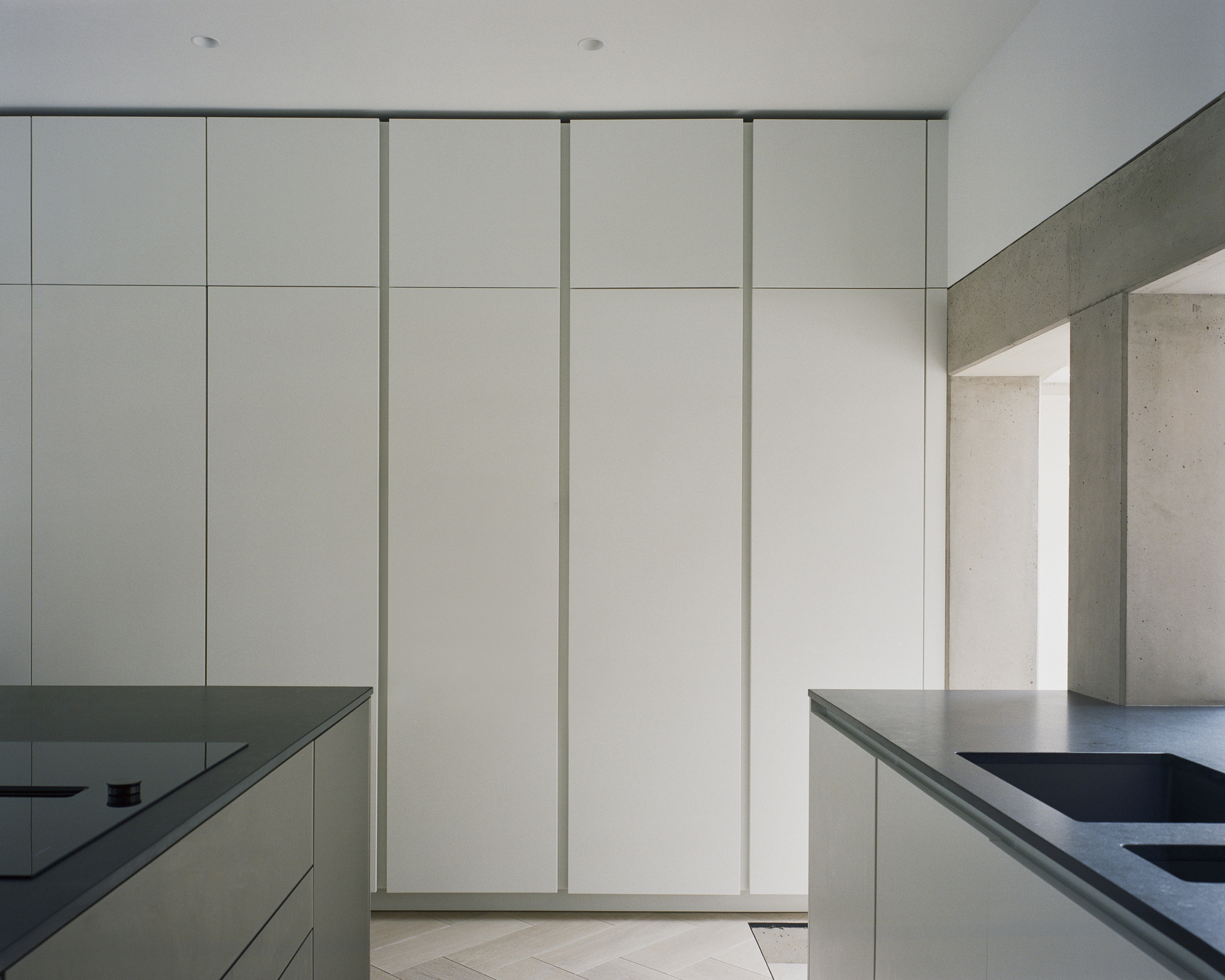 Full-height white storage wall with jointed panels flanked by concrete structure