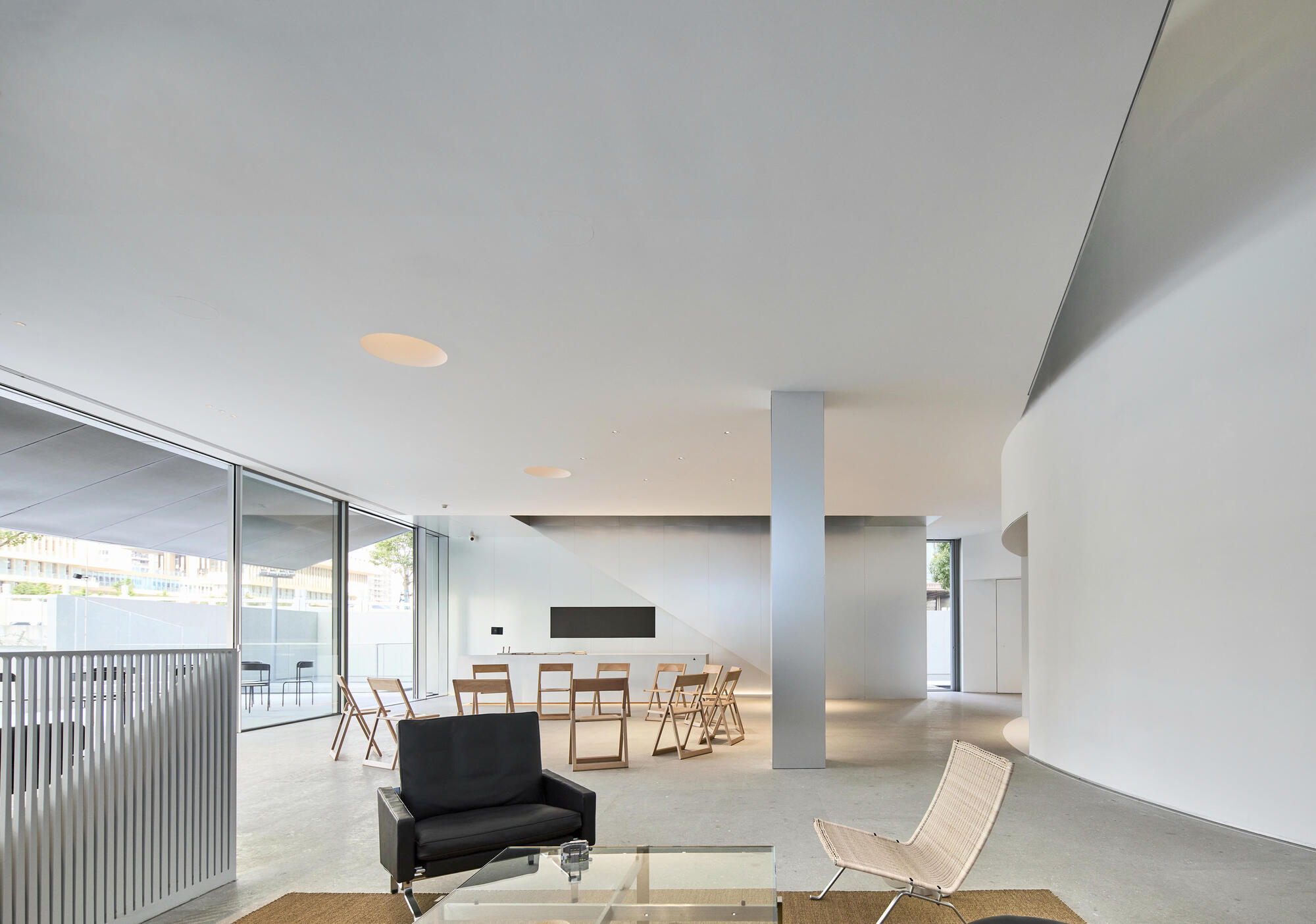 Open-plan interior with white ceiling, terrazzo flooring and full-height glazing opening to a terrace