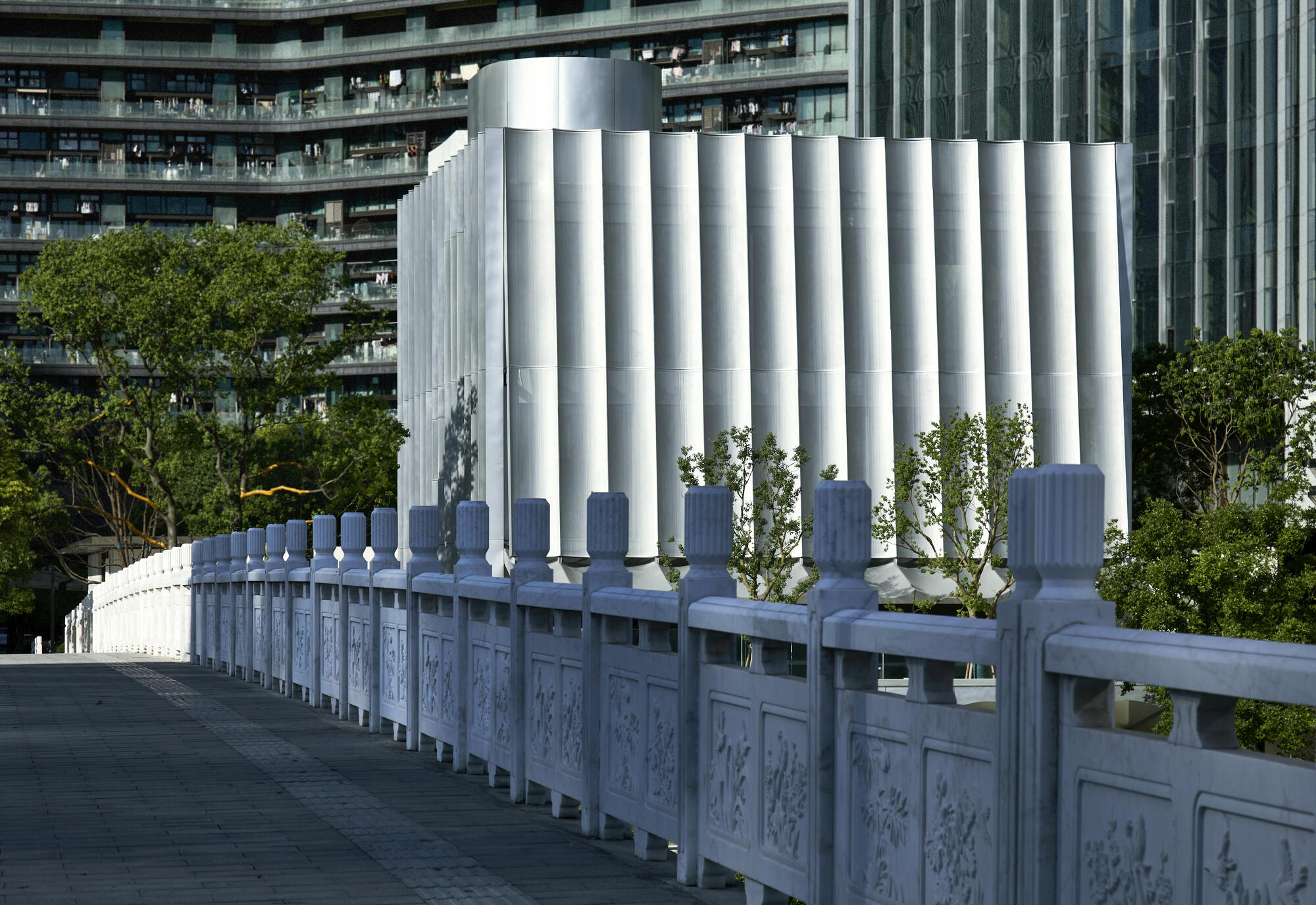 White cylindrical columns rising behind ornamental stone railing with carved panels and balusters