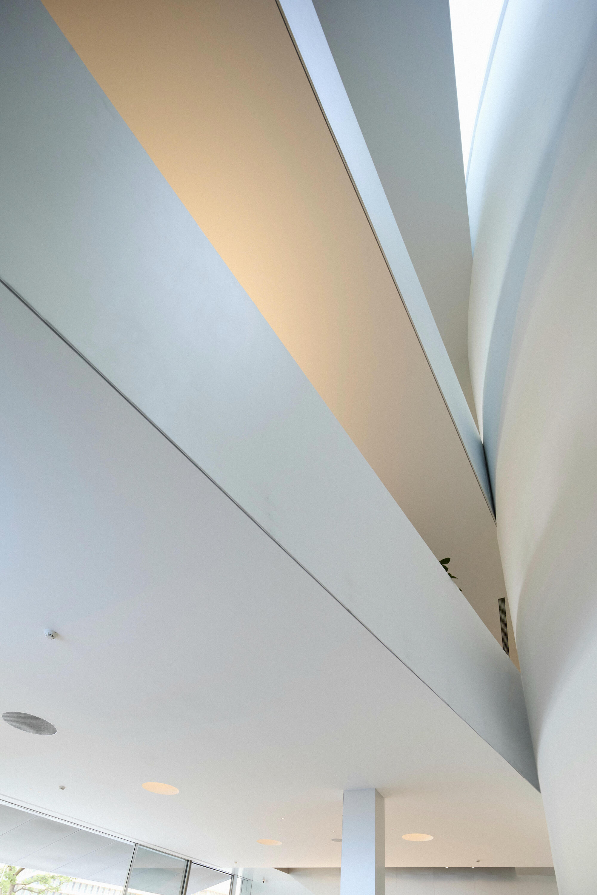 Clerestory window slicing through angled ceiling planes above a white interior volume