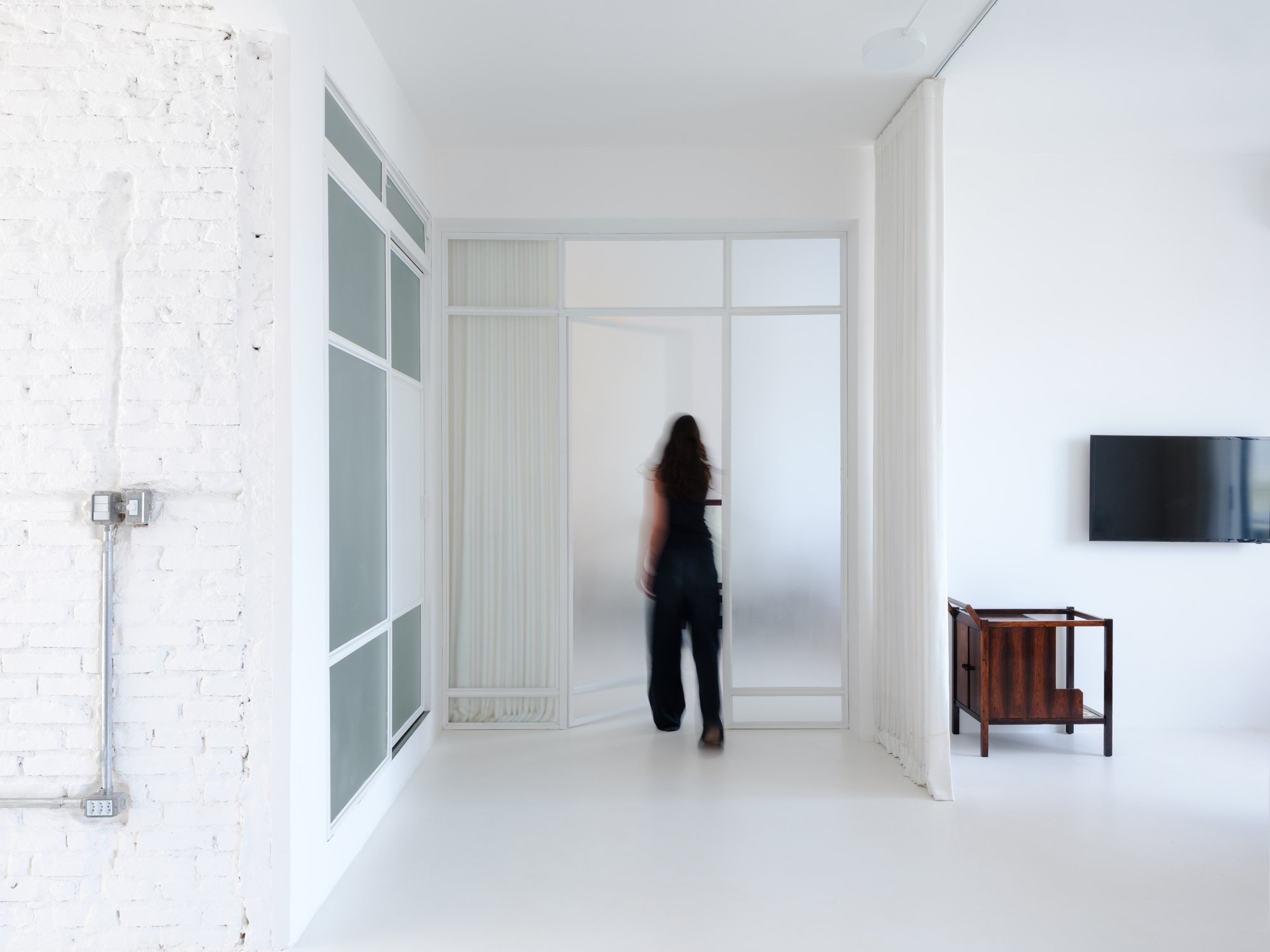 Hallway view showing painted brick wall and figure standing by frosted glass doors