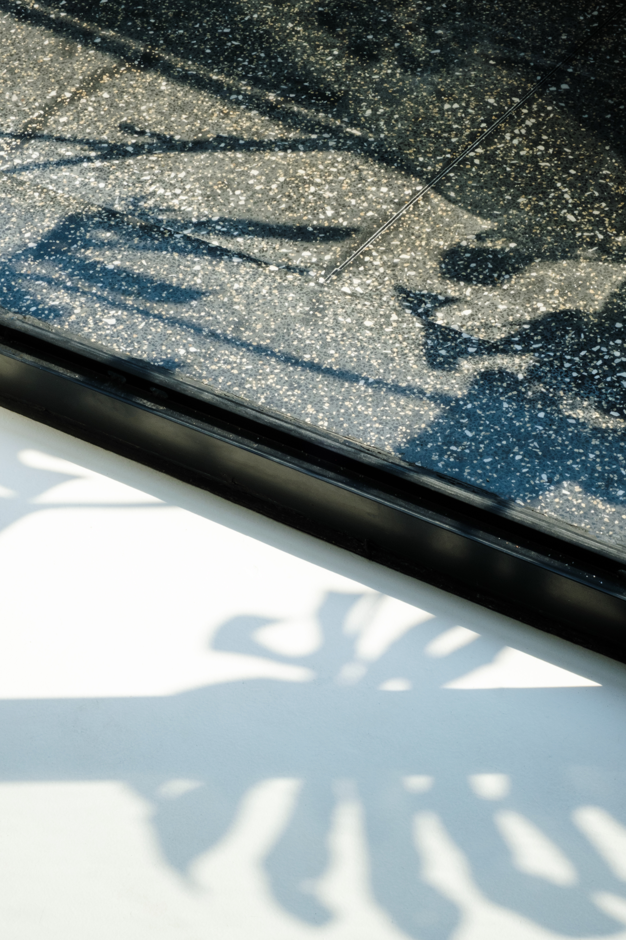 Detail of terrazzo flooring with blue and white aggregate pattern meeting a dark metal threshold