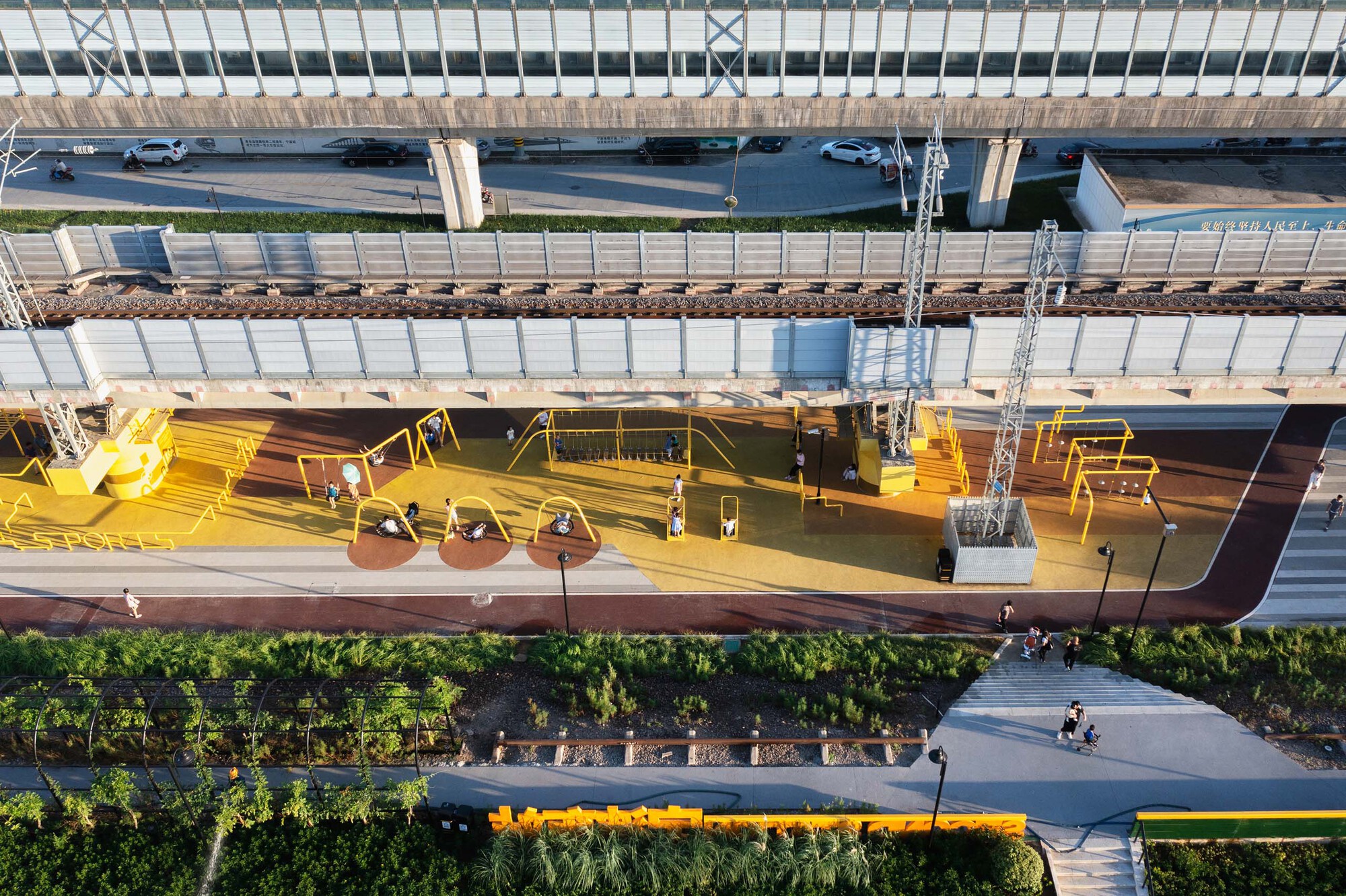 Overhead view of yellow platform surface with exercise equipment beneath elevated tracks and arched canopy