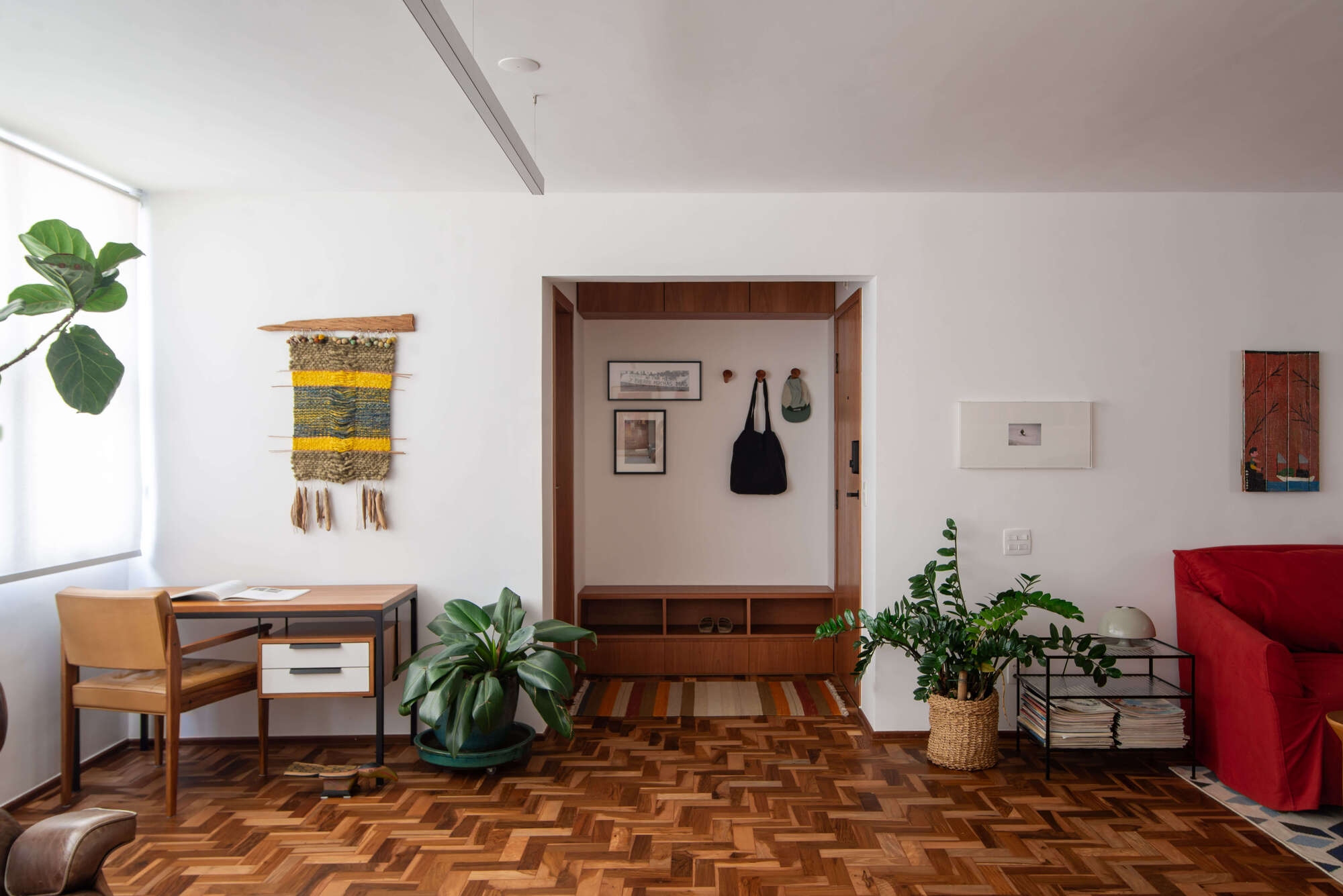 Custom timber entry niche with coat hooks and storage drawers flanked by potted plants