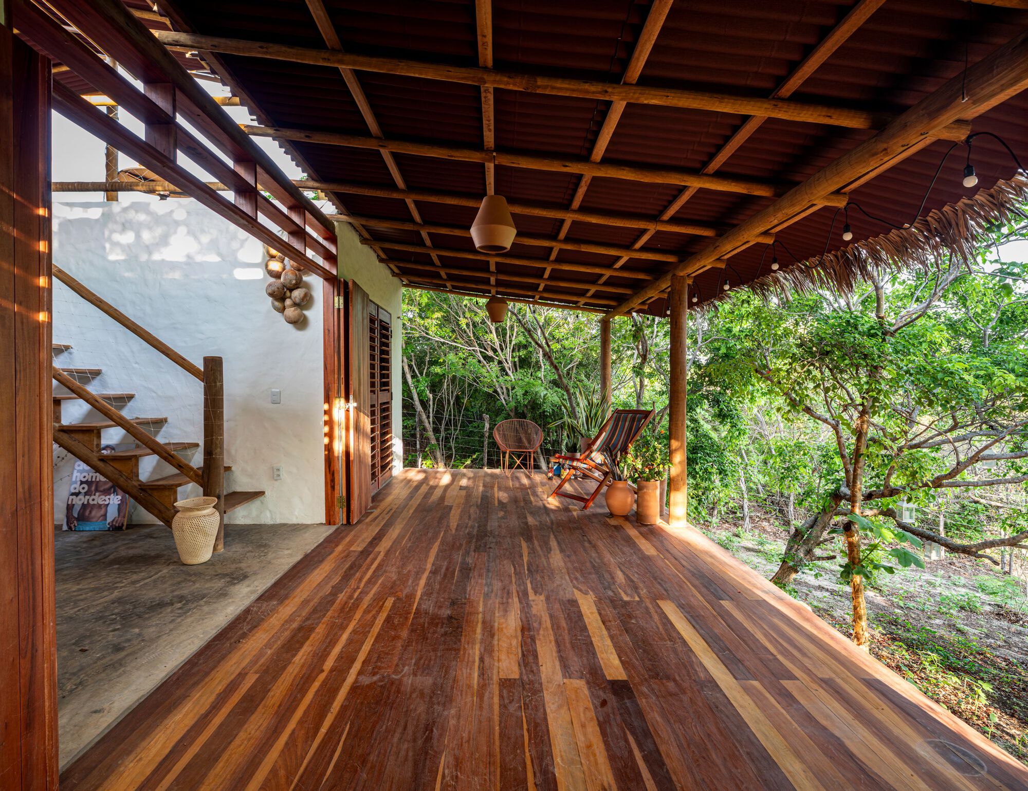 Open timber deck terrace with exposed beam ceiling and wooden staircase framing views to surrounding forest