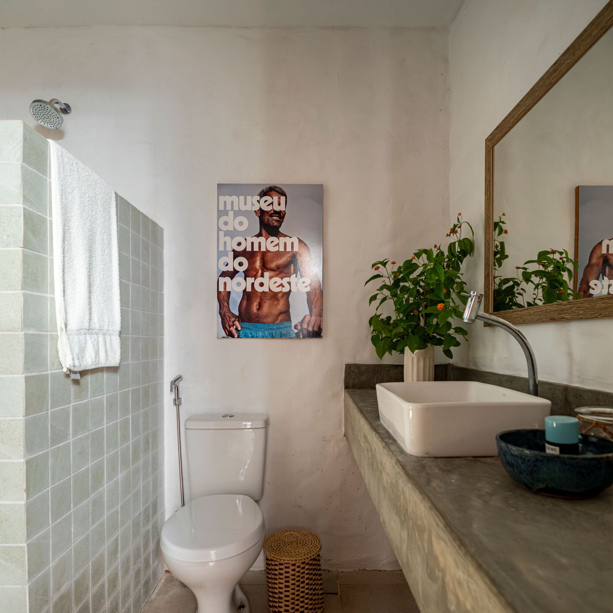 Bathroom with pale green tiled shower enclosure and concrete vanity with vessel sink under soft daylight